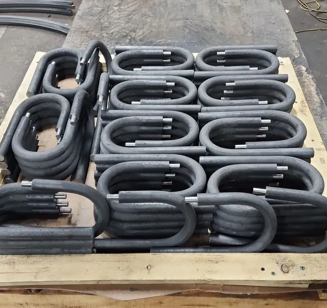 Stacks of U-shaped metal pipes with insulated sections, on a wooden pallet.