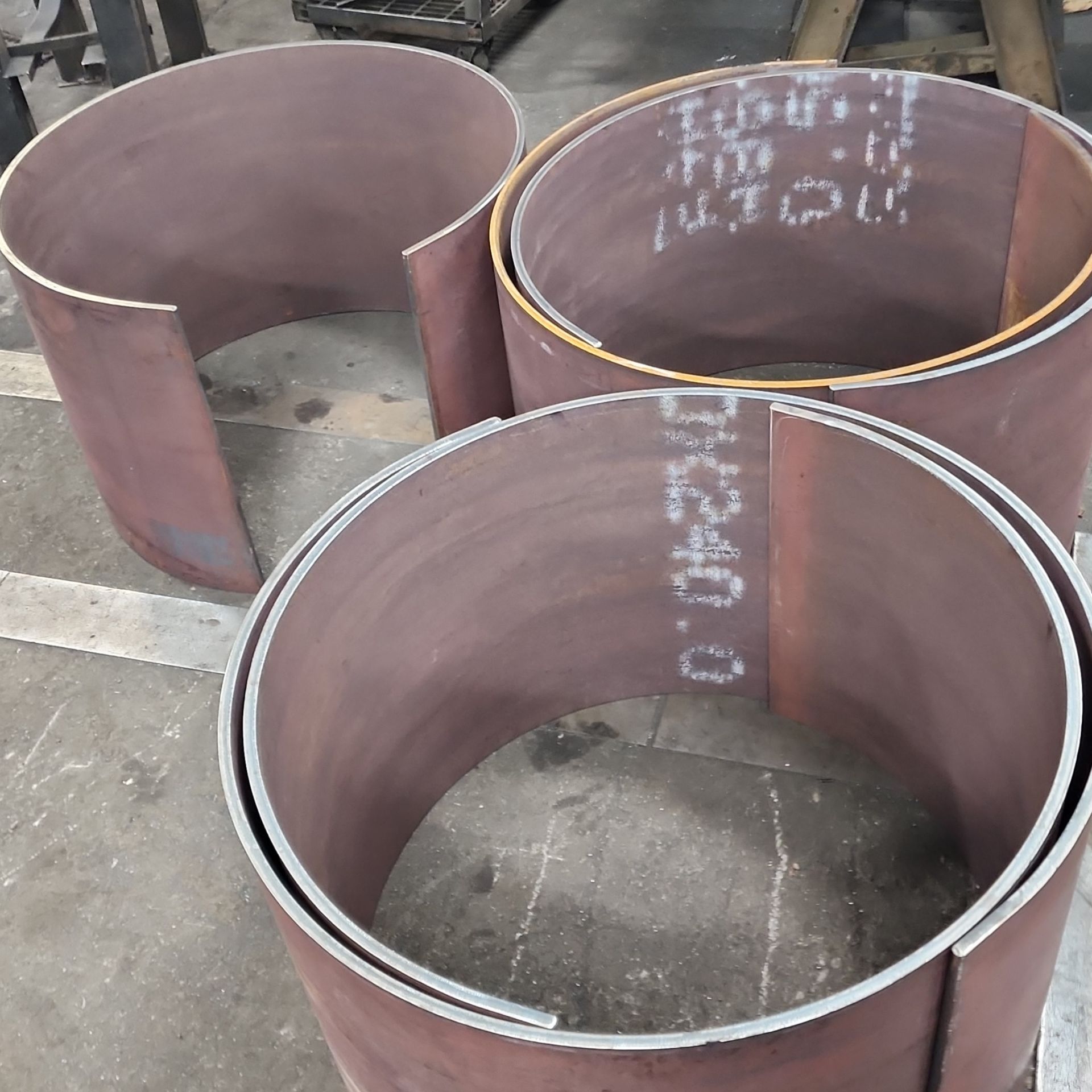 Three cylindrical metal pieces lying on a surface; they are brown, and one has writing.