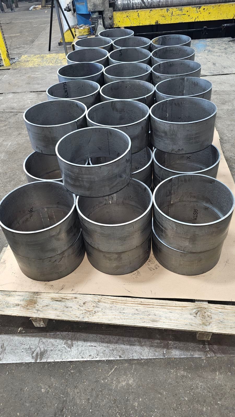 Metal cylinders stacked on a pallet in a workshop setting.