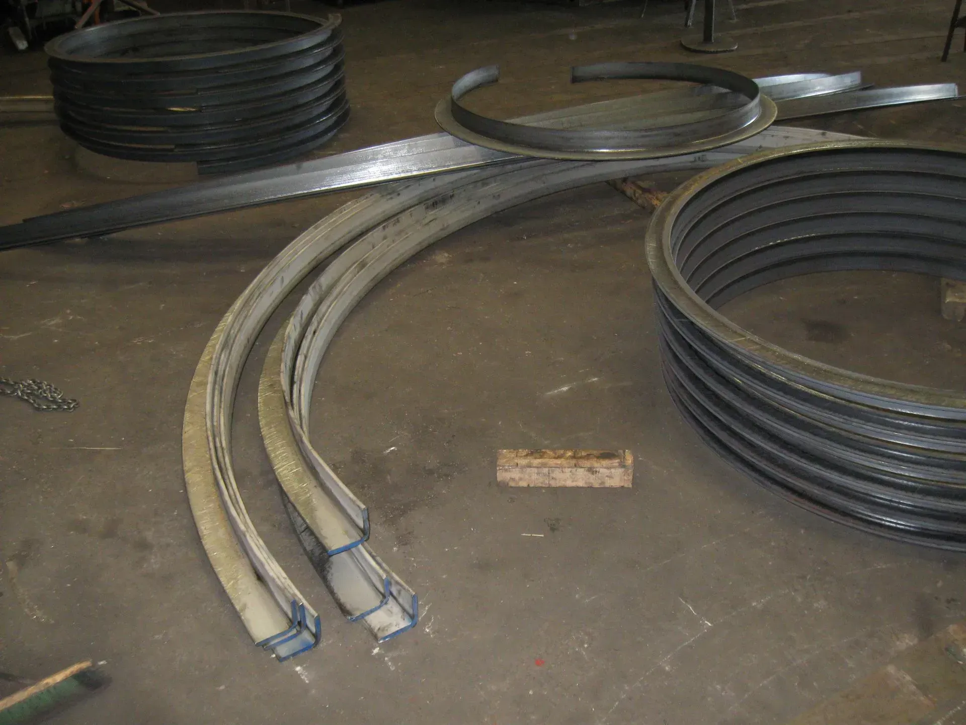 Steel rings and curved metal pieces on a gray floor, likely for construction or manufacturing.
