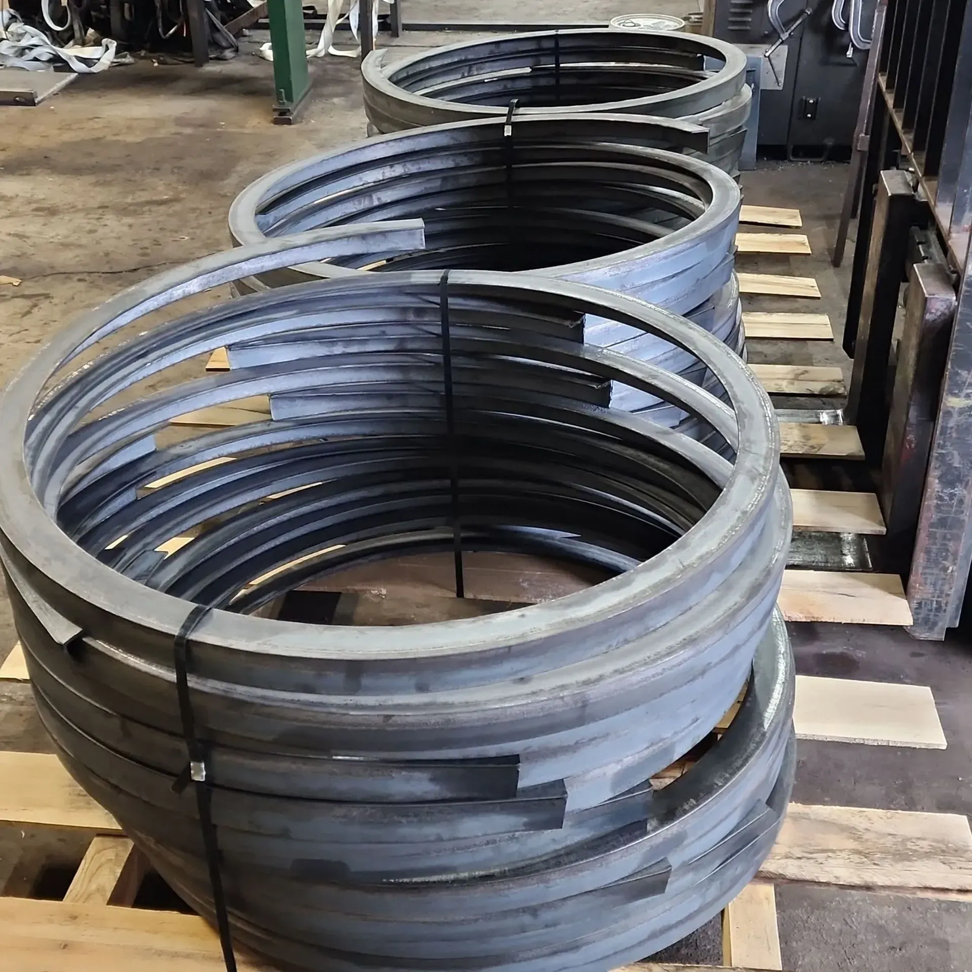 Bundled metal rings stacked on a wooden pallet in a workshop.