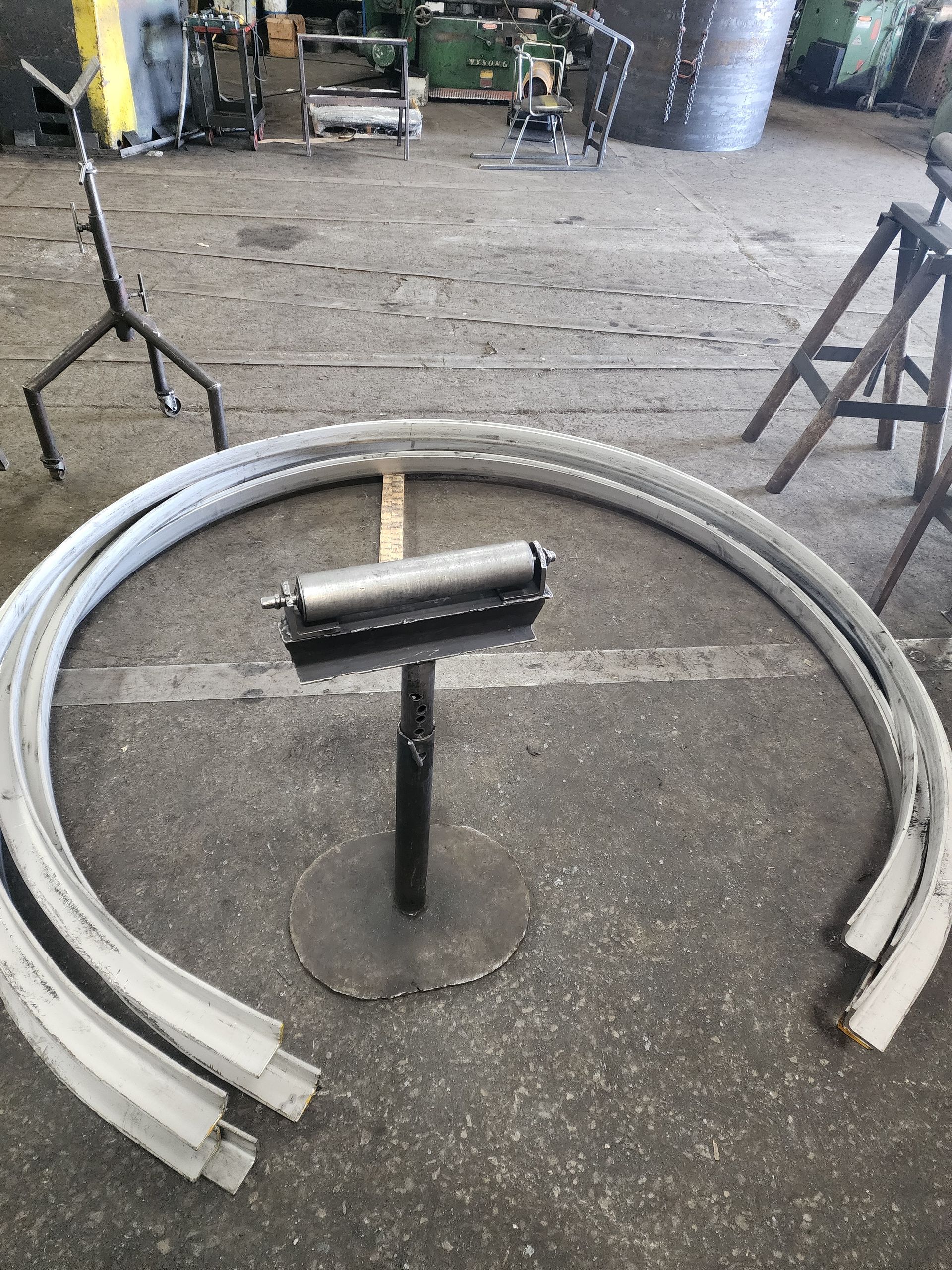 Curved metal pieces and a roller stand in a workshop setting.