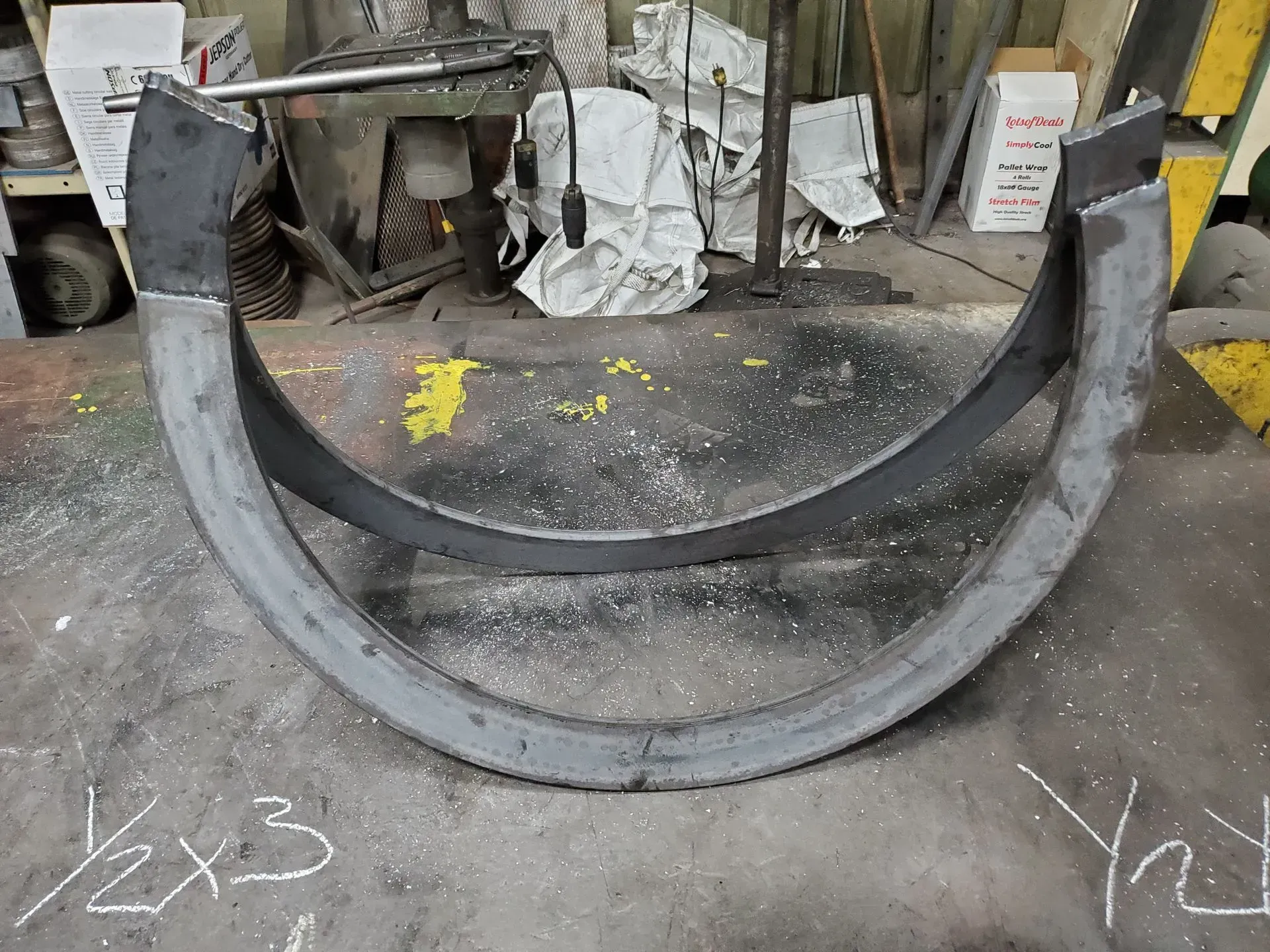 Steel arc-shaped structure on a gray floor, possibly a metal fabrication shop.