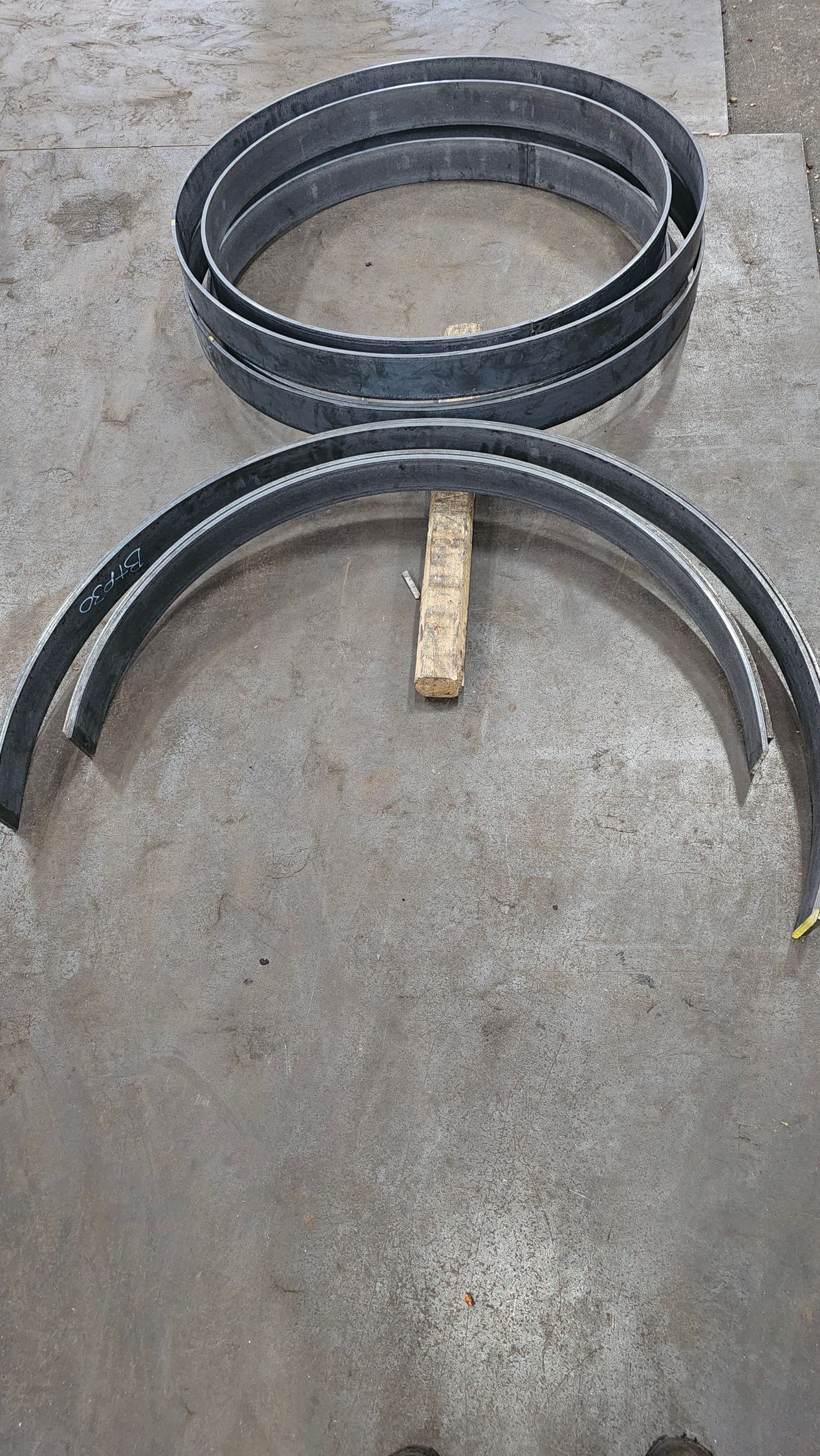 Two black, semi-circular metal bands and two complete bands on a concrete surface.