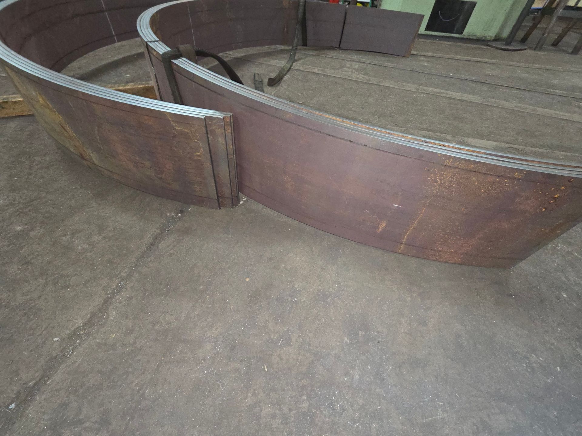 Curved metal plates on a concrete floor, likely for construction.