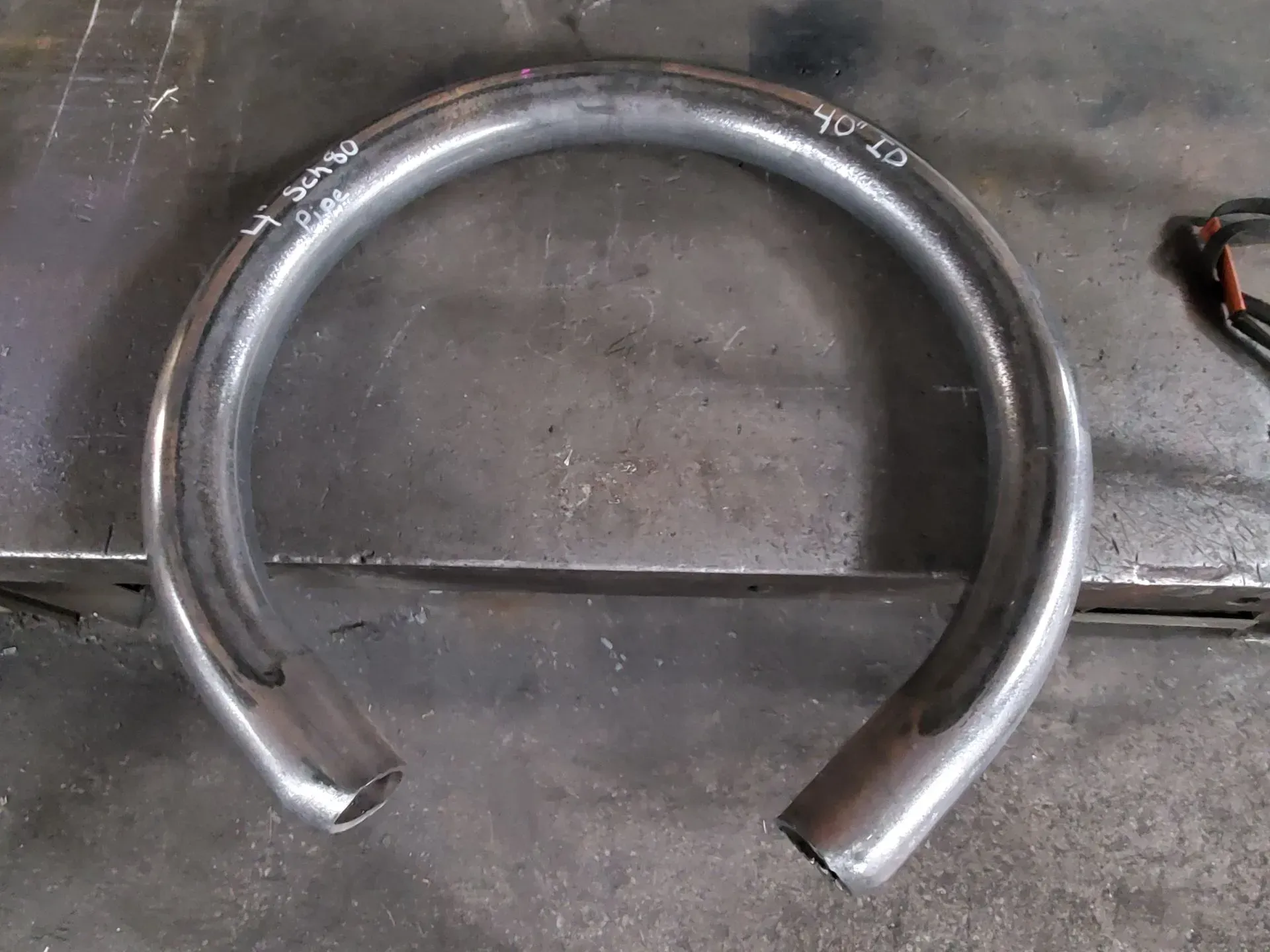 Bent metal tube, possibly for construction, on a metal surface.