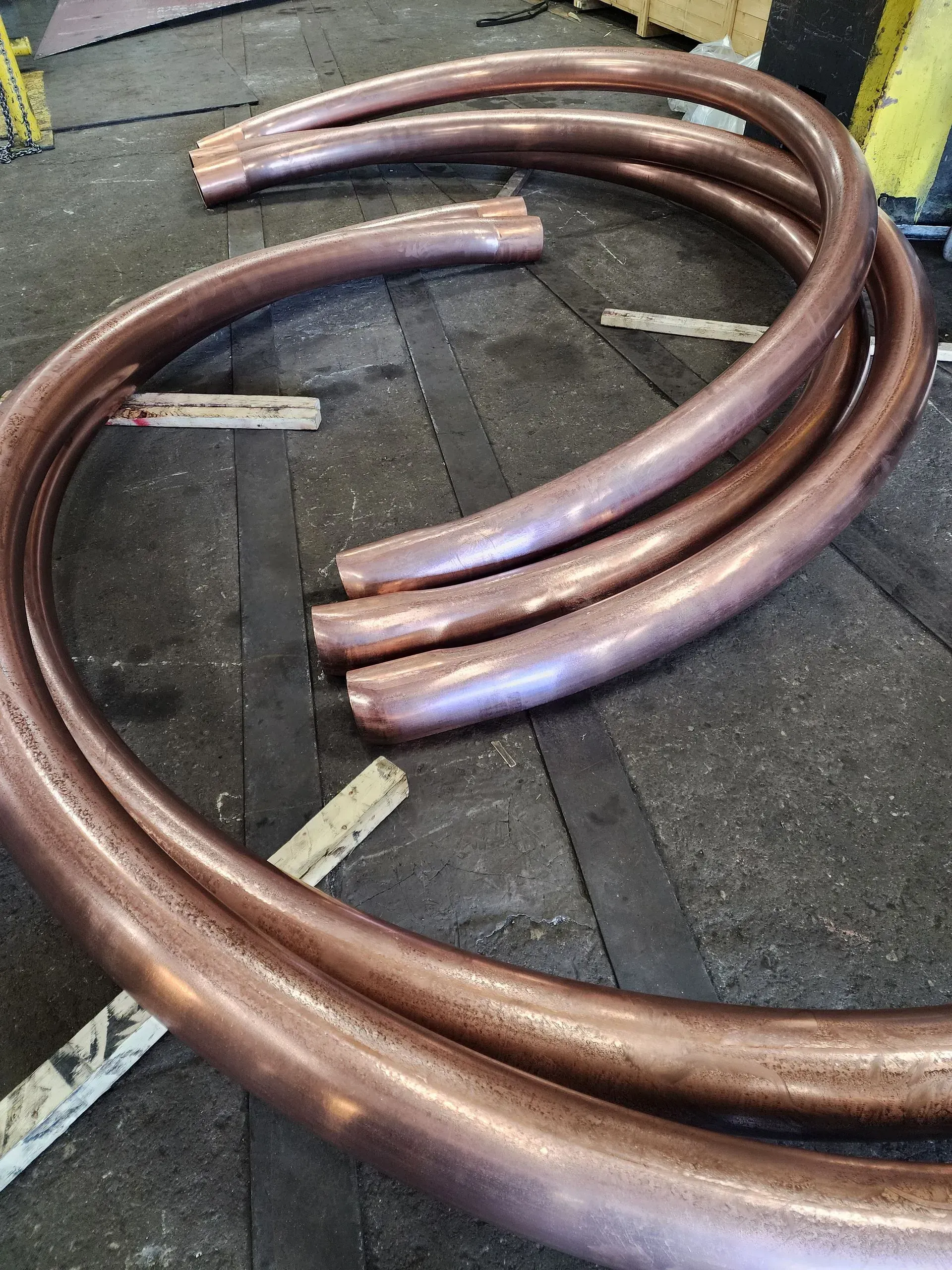 Curved copper pipes arranged on a dark surface.