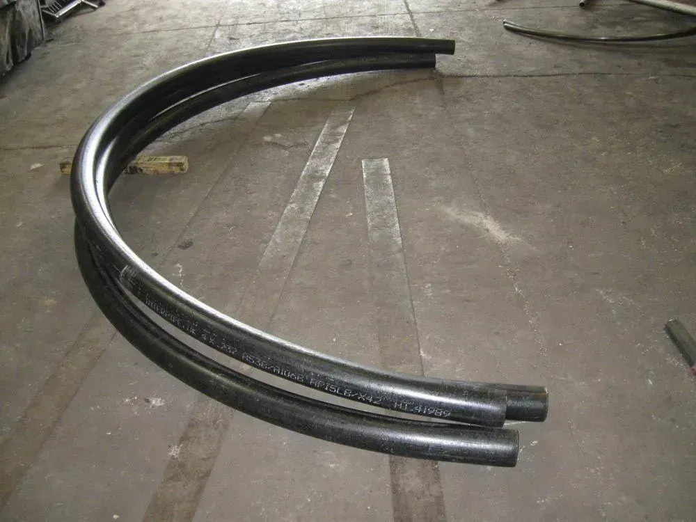 Black, curved pipes on a concrete floor.