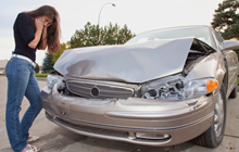Upset woman standing beside her damaged car