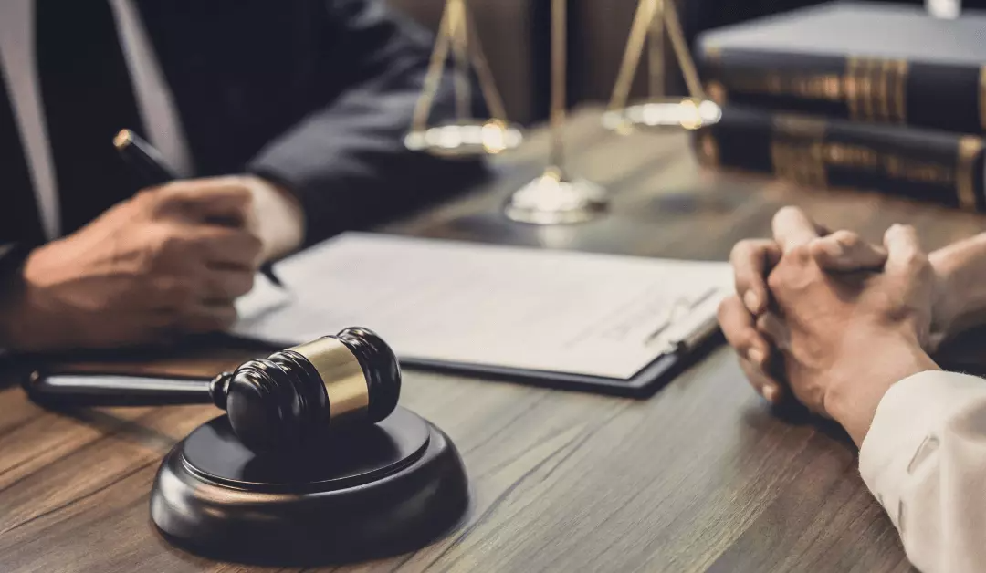 Lawyer's desk with gavel, documents, and two people discussing a case