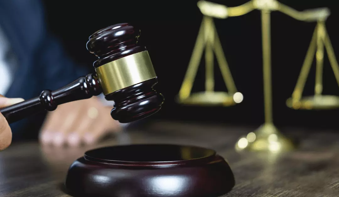 Judge’s gavel over sound block with scales of justice in the background