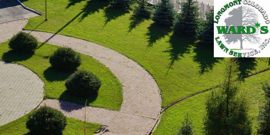 Overhead view of a landscaped area with grass, trees, and a stone walkway. A logo for