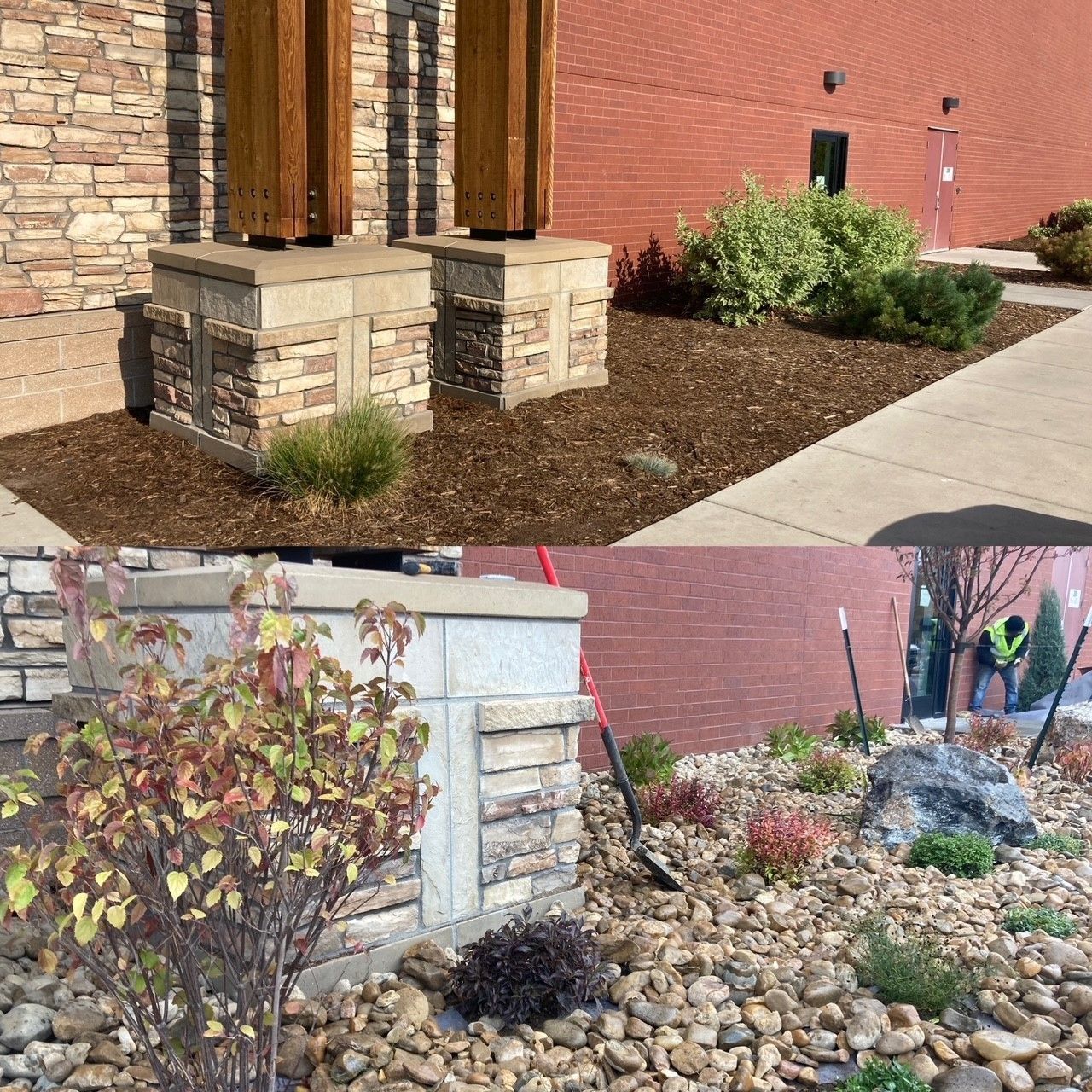 Landscaped brick building corner with stone columns, mulch beds, shrubs, and a small rock feature