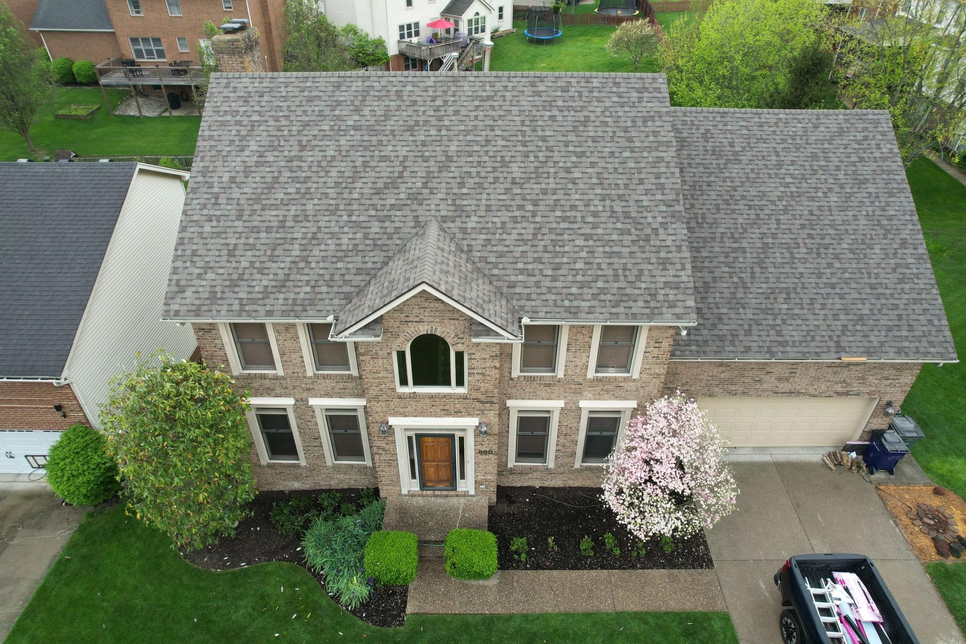 An aerial view of a large brick house with a gray roof.