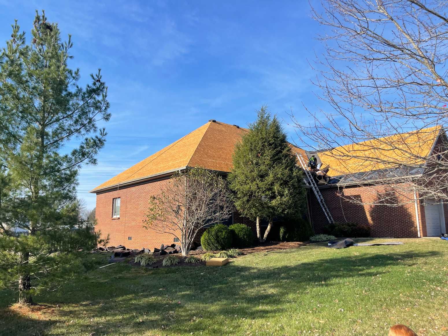 A large brick house with a roof that is being installed.