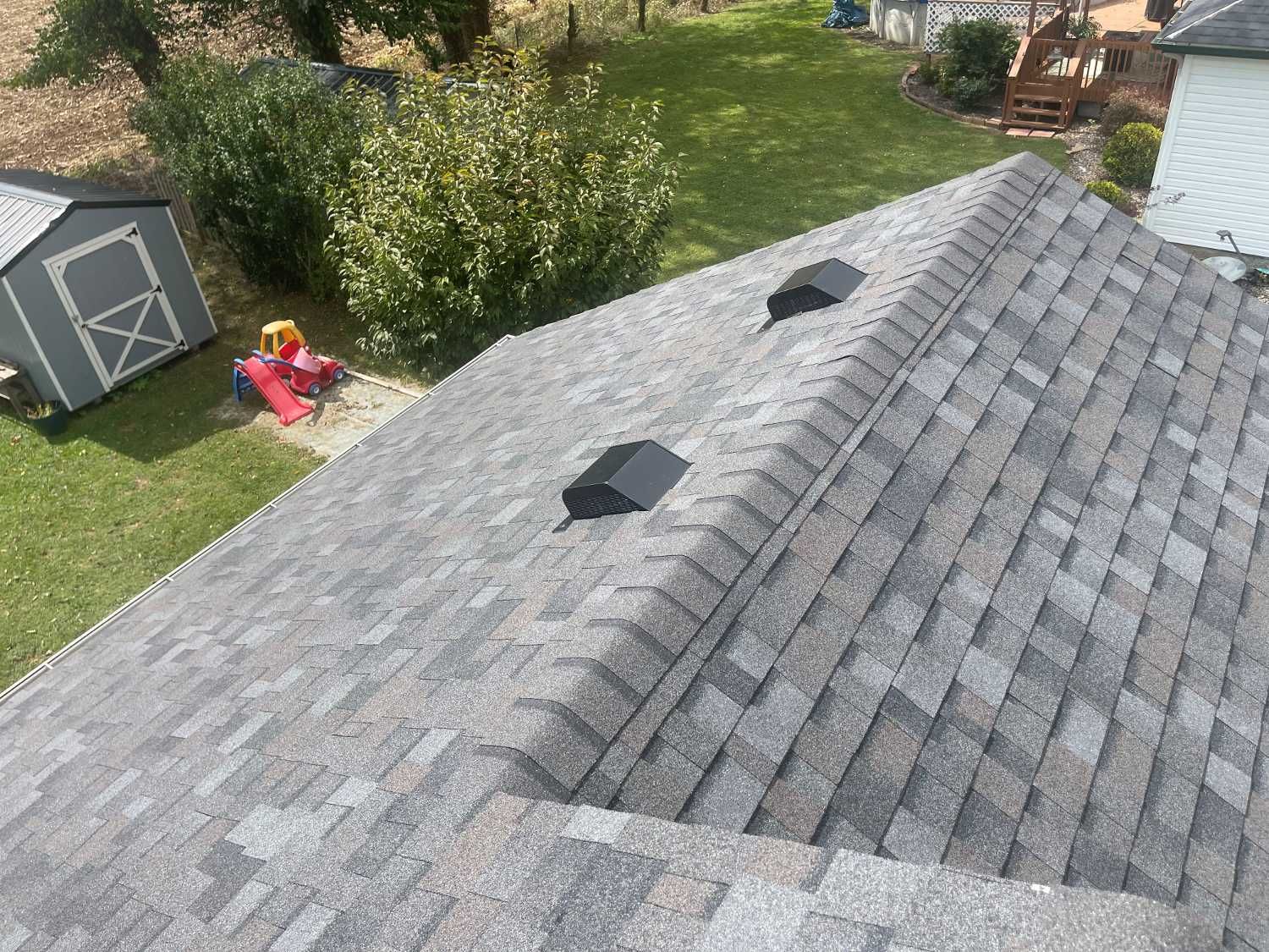 An aerial view of a roof with a shed in the background.