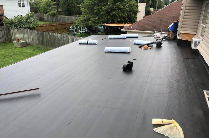 A black roof is being installed on a house.