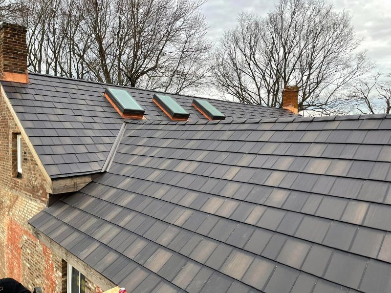 A roof with three skylights on it and a chimney.