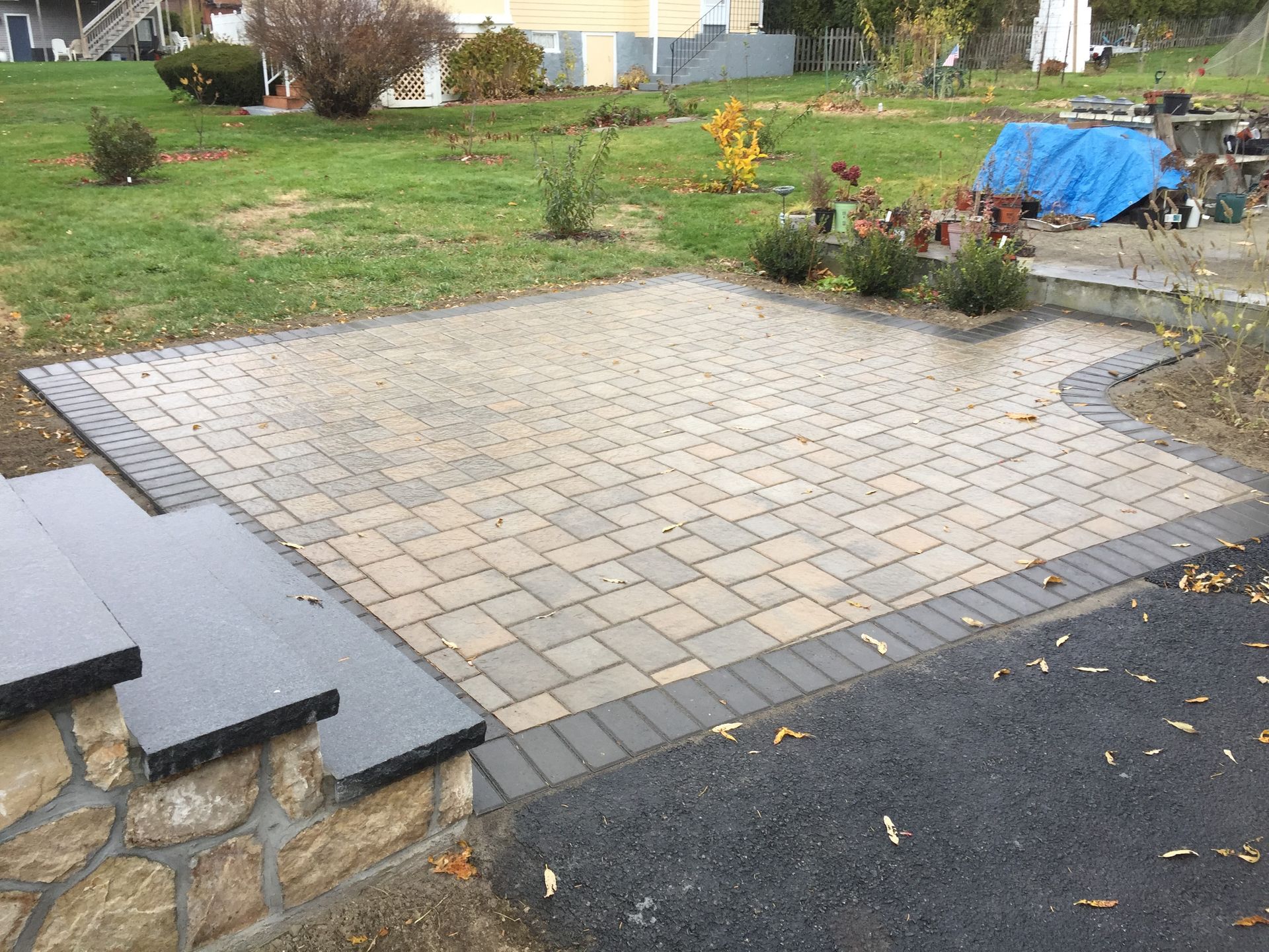 A brick patio with stairs leading up to it in a backyard.