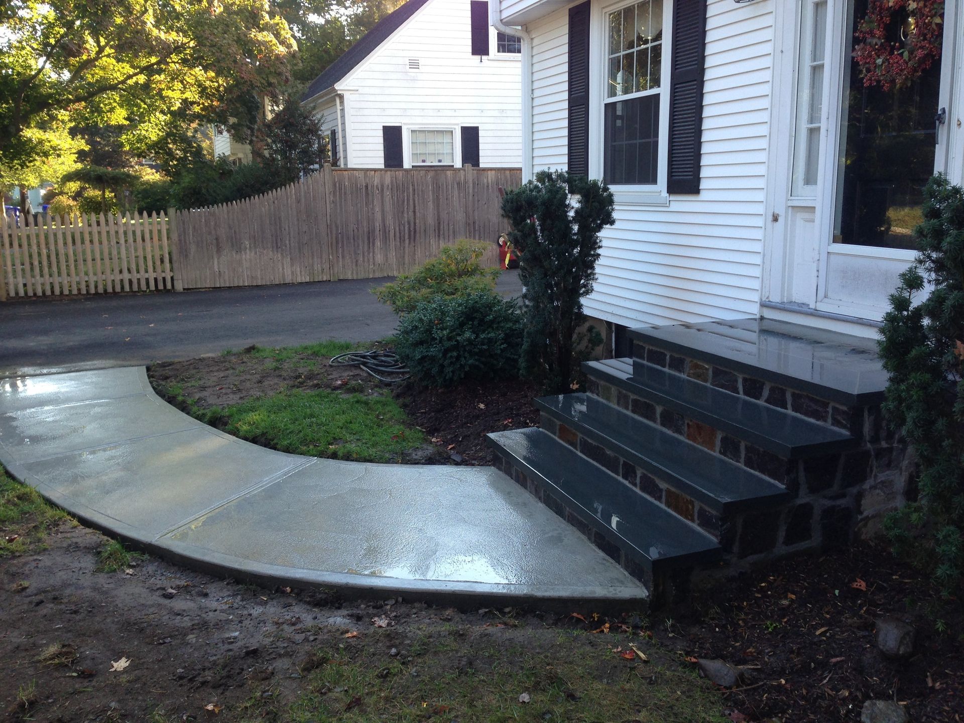 A white house with a curved concrete walkway leading to the front door