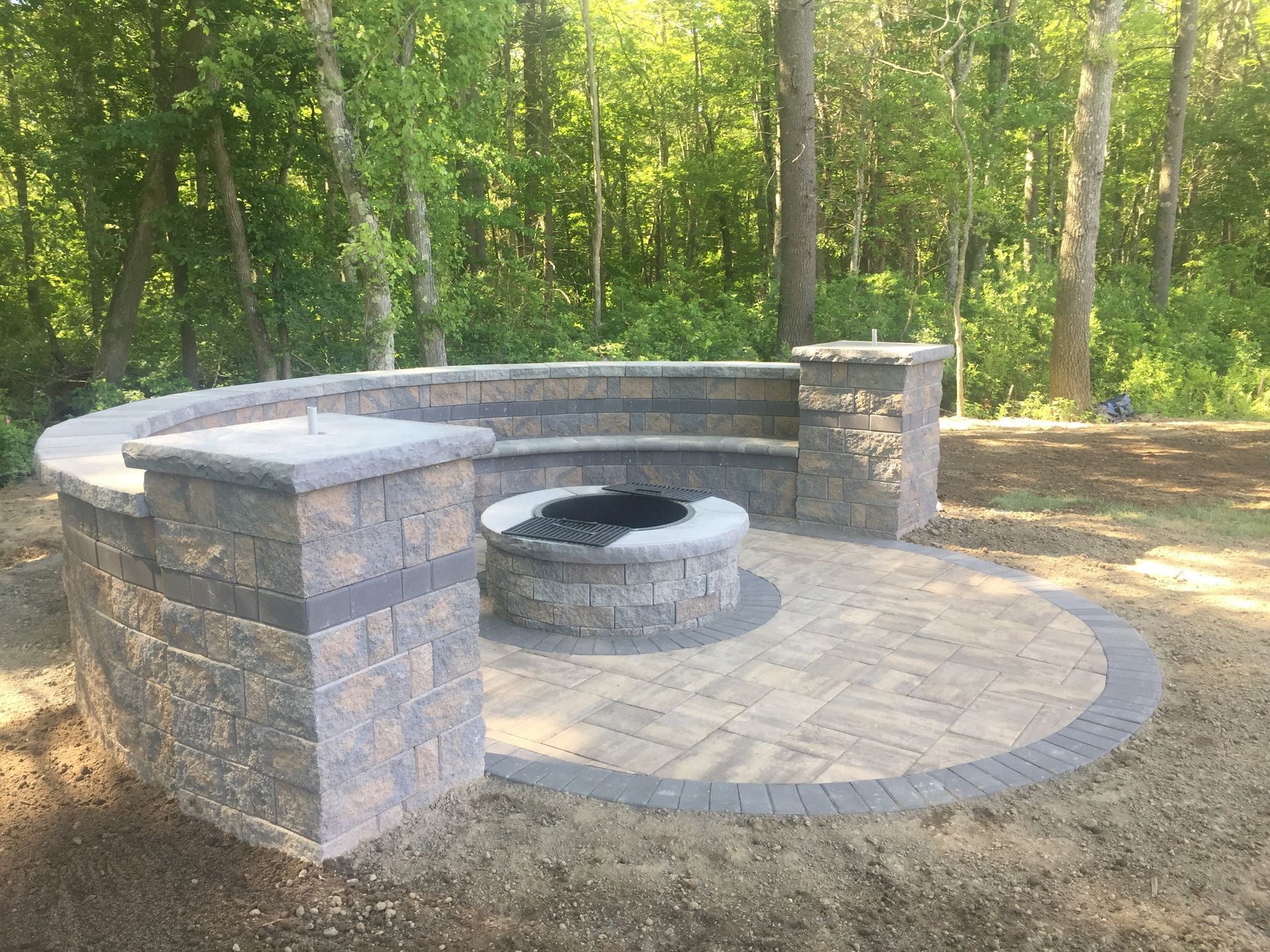 There is a fire pit in the middle of the patio surrounded by trees.
