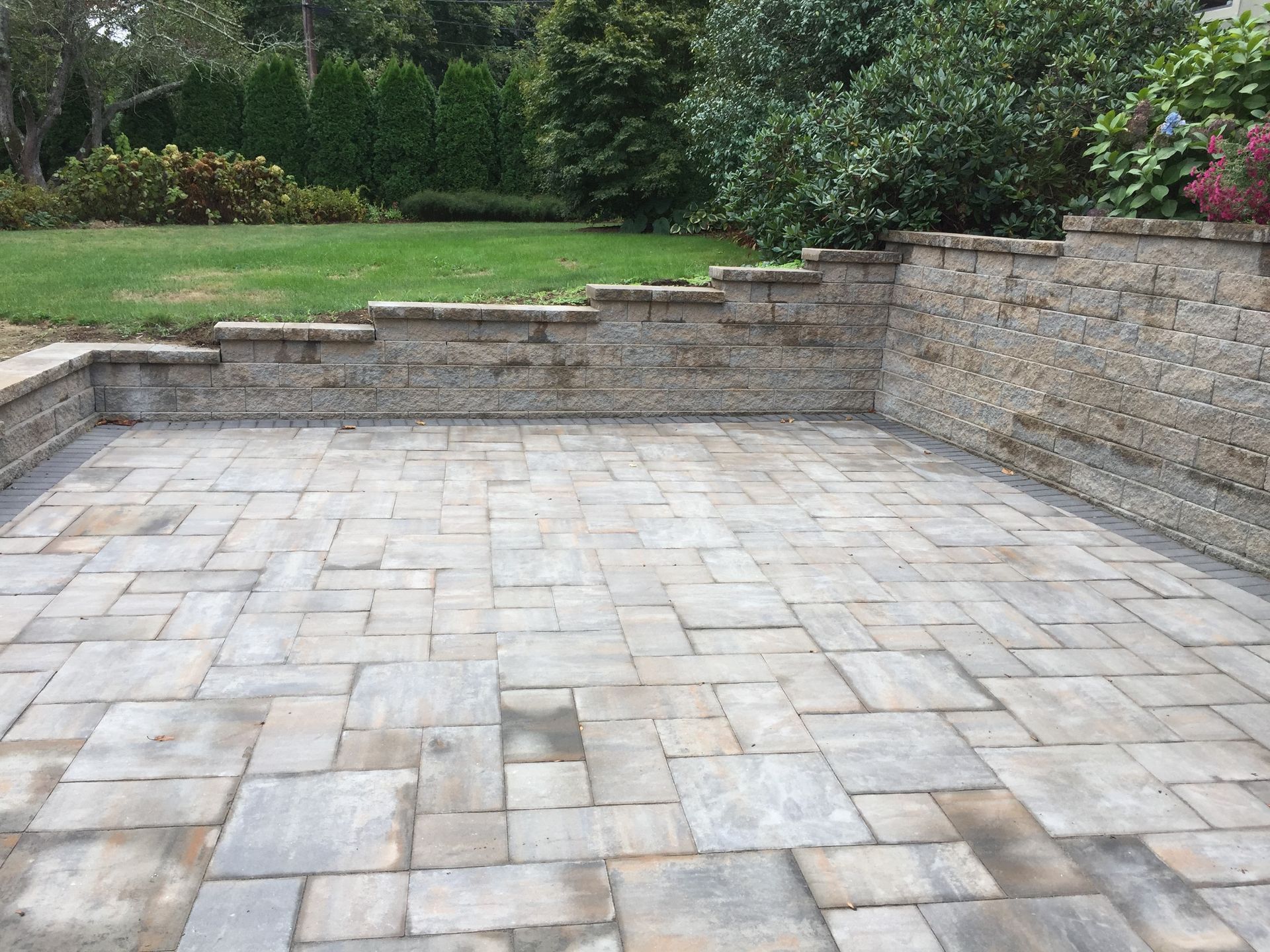 A brick patio with a stone wall in the background