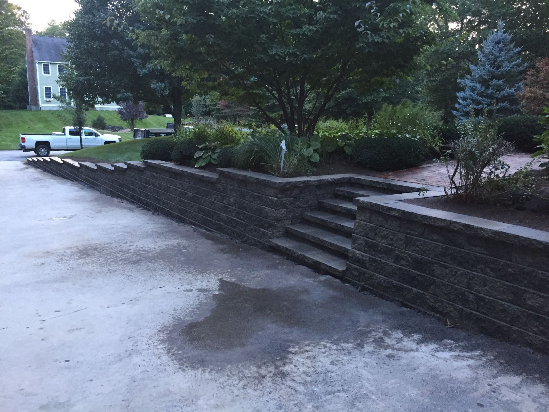 A white truck is parked in a driveway next to a stone wall