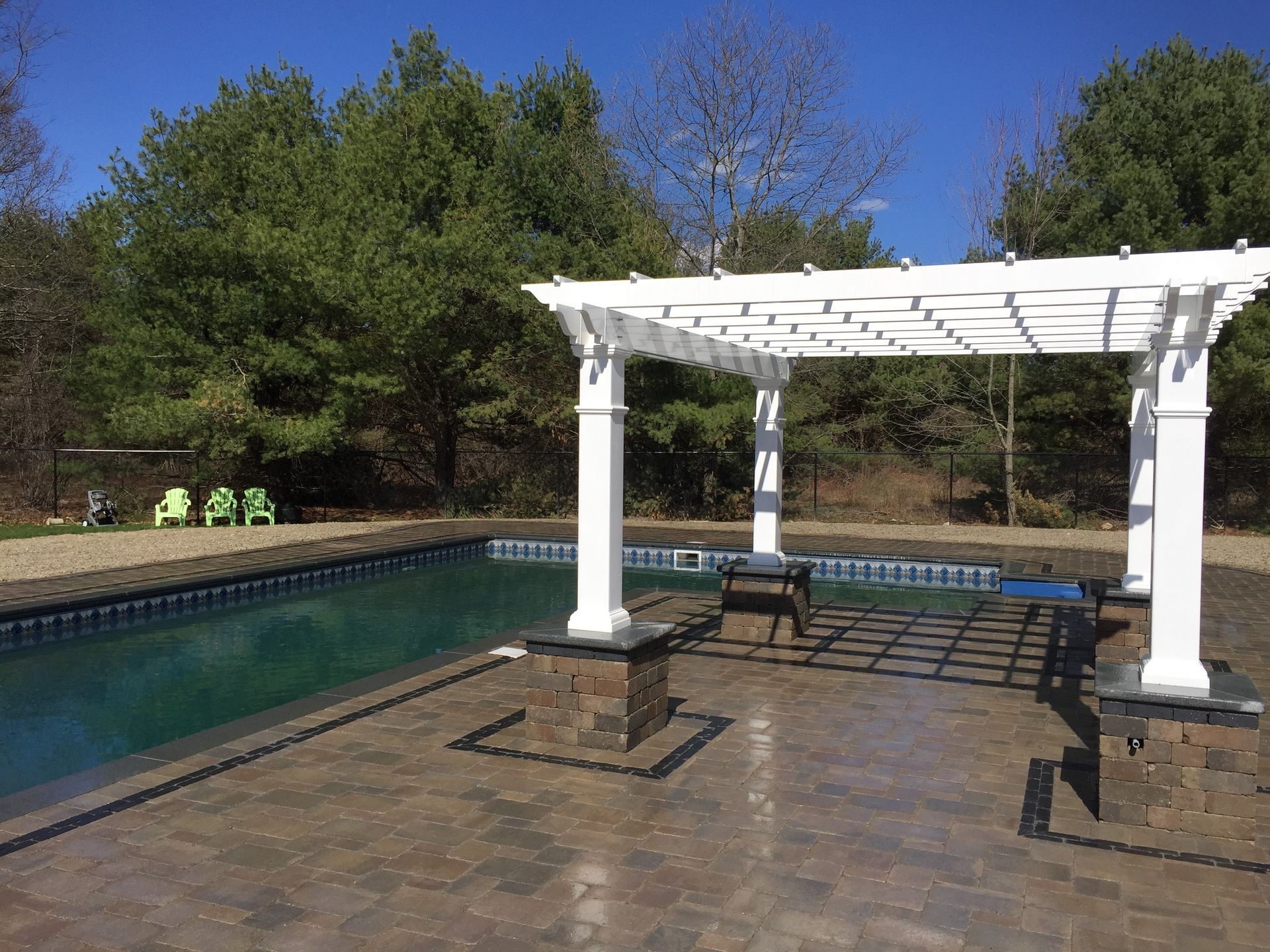 A white pergola is sitting next to a swimming pool.