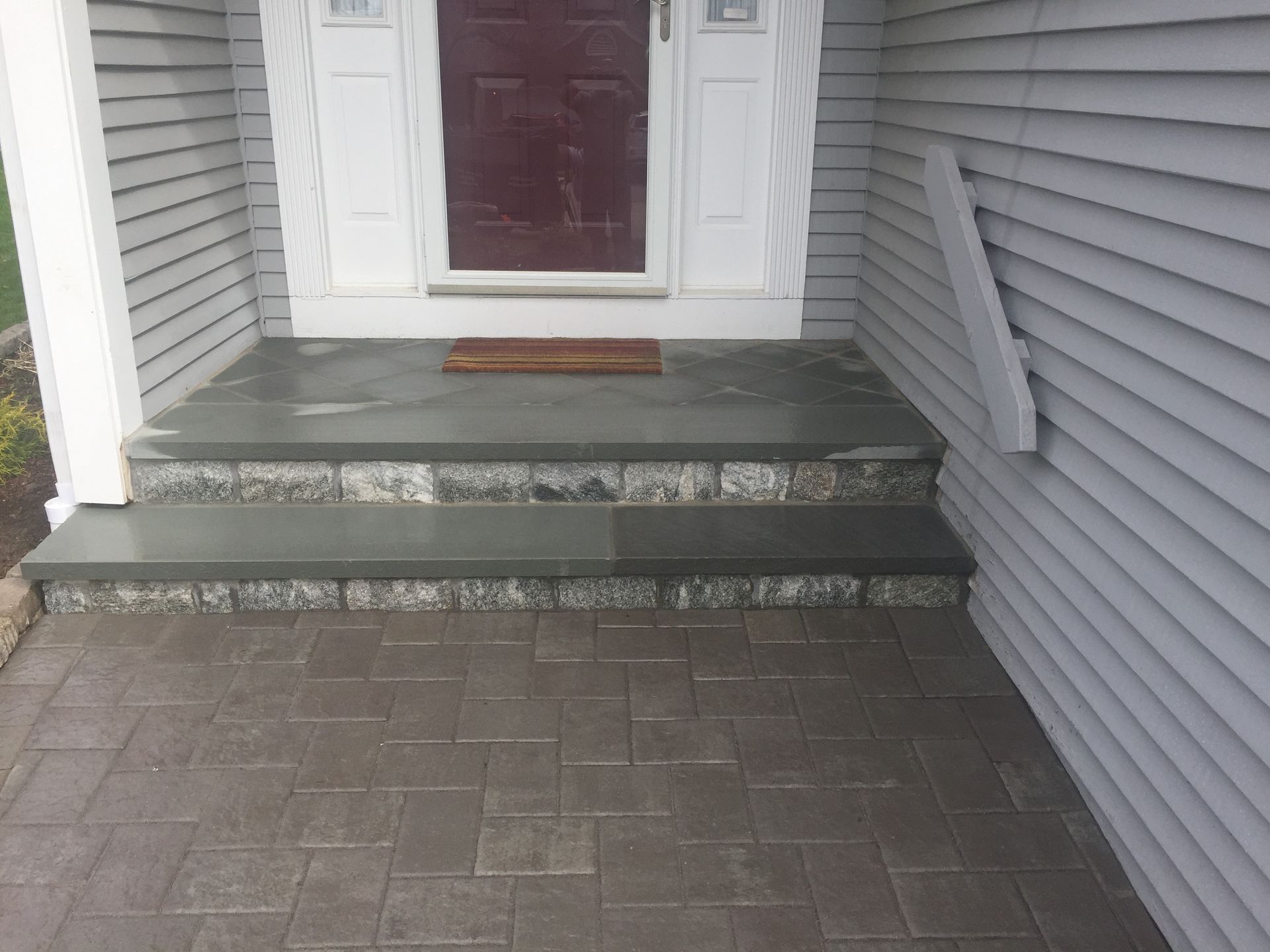 A brick walkway leading to a front door of a house