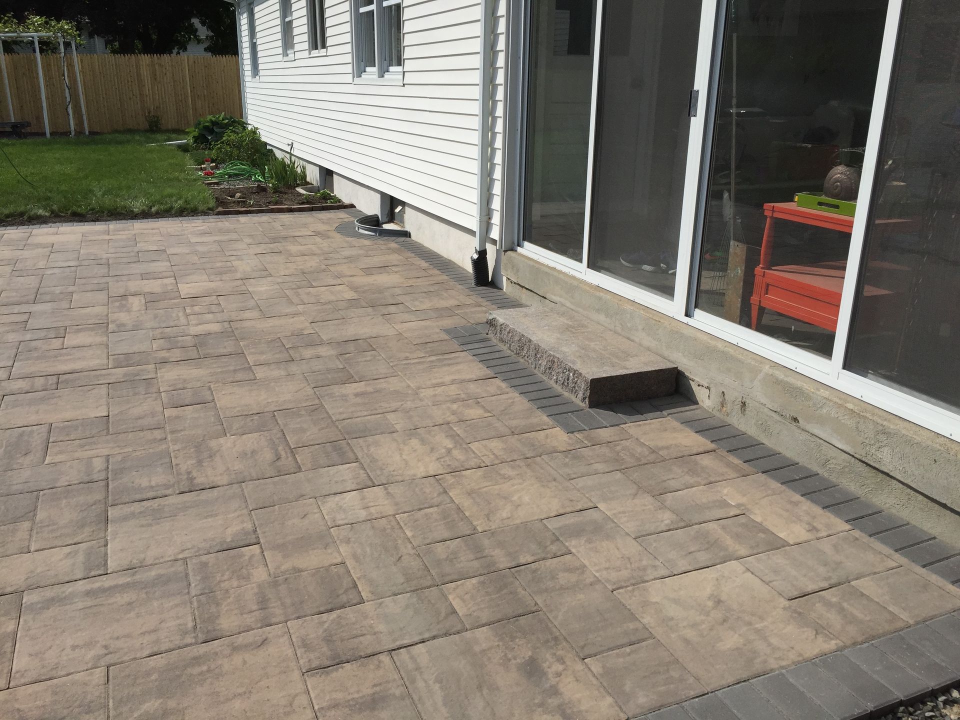 A patio with a sliding glass door in front of a house.