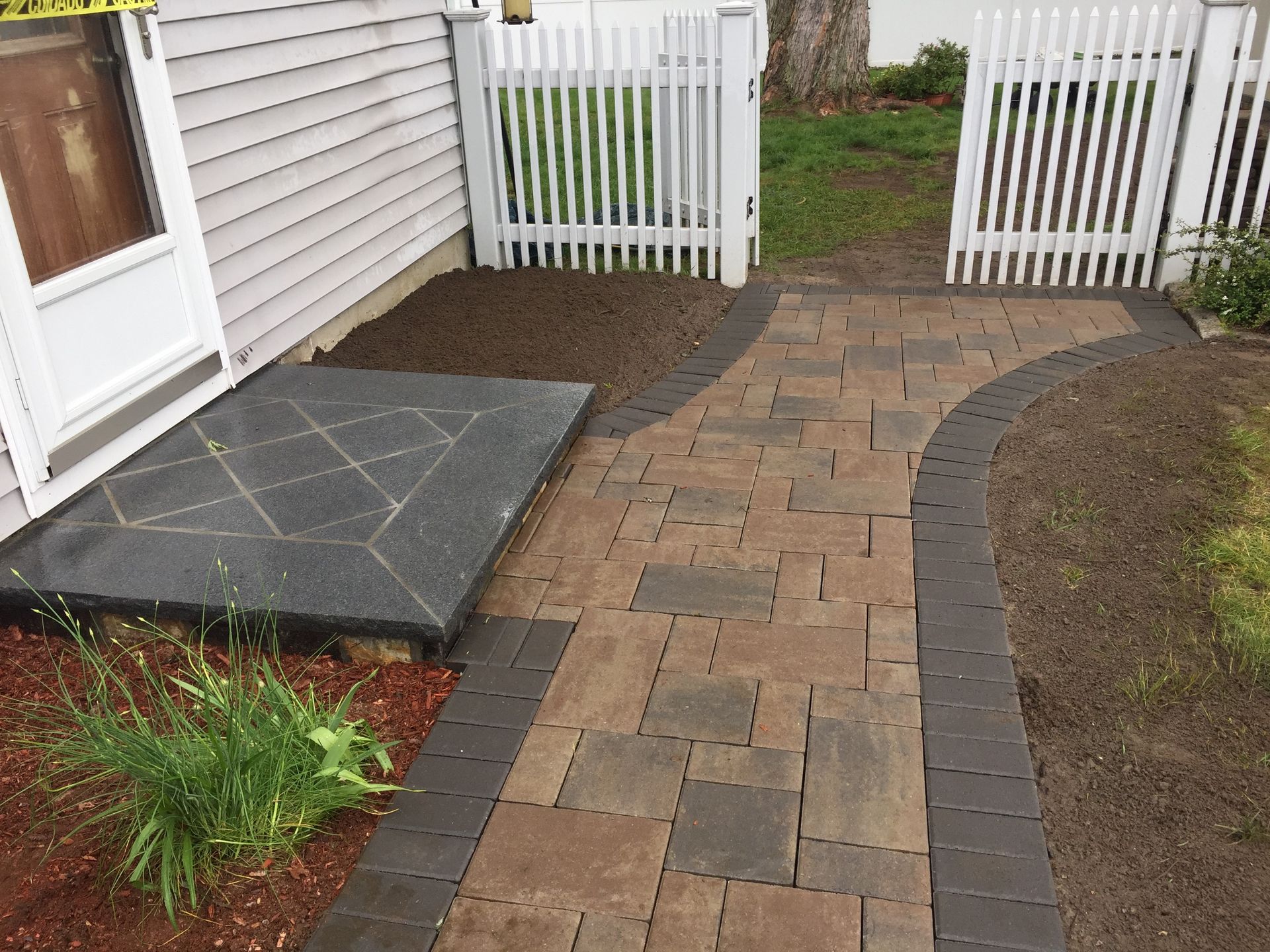 A walkway leading to a house with a white picket fence