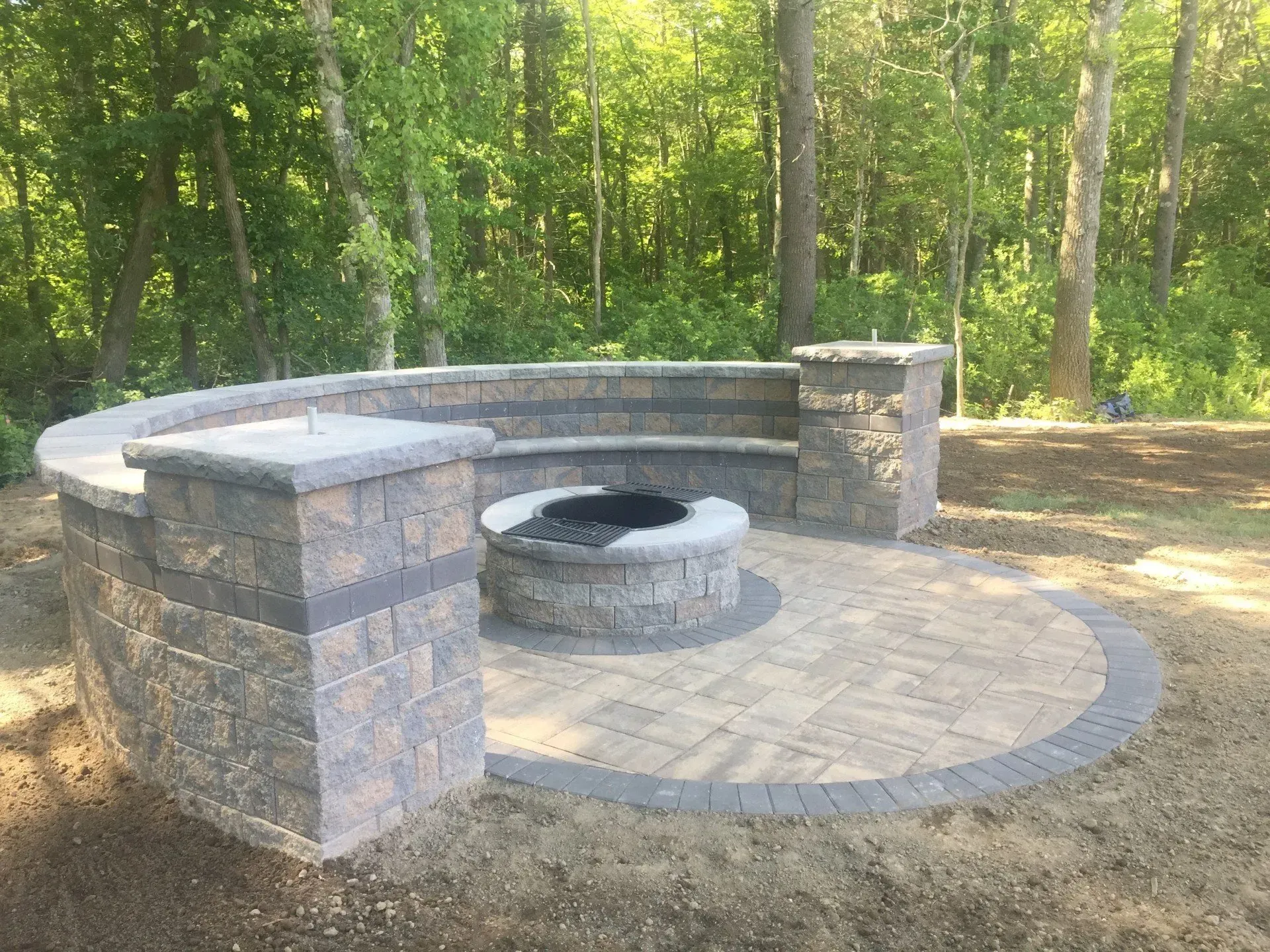 There is a fire pit in the middle of the patio surrounded by trees.
