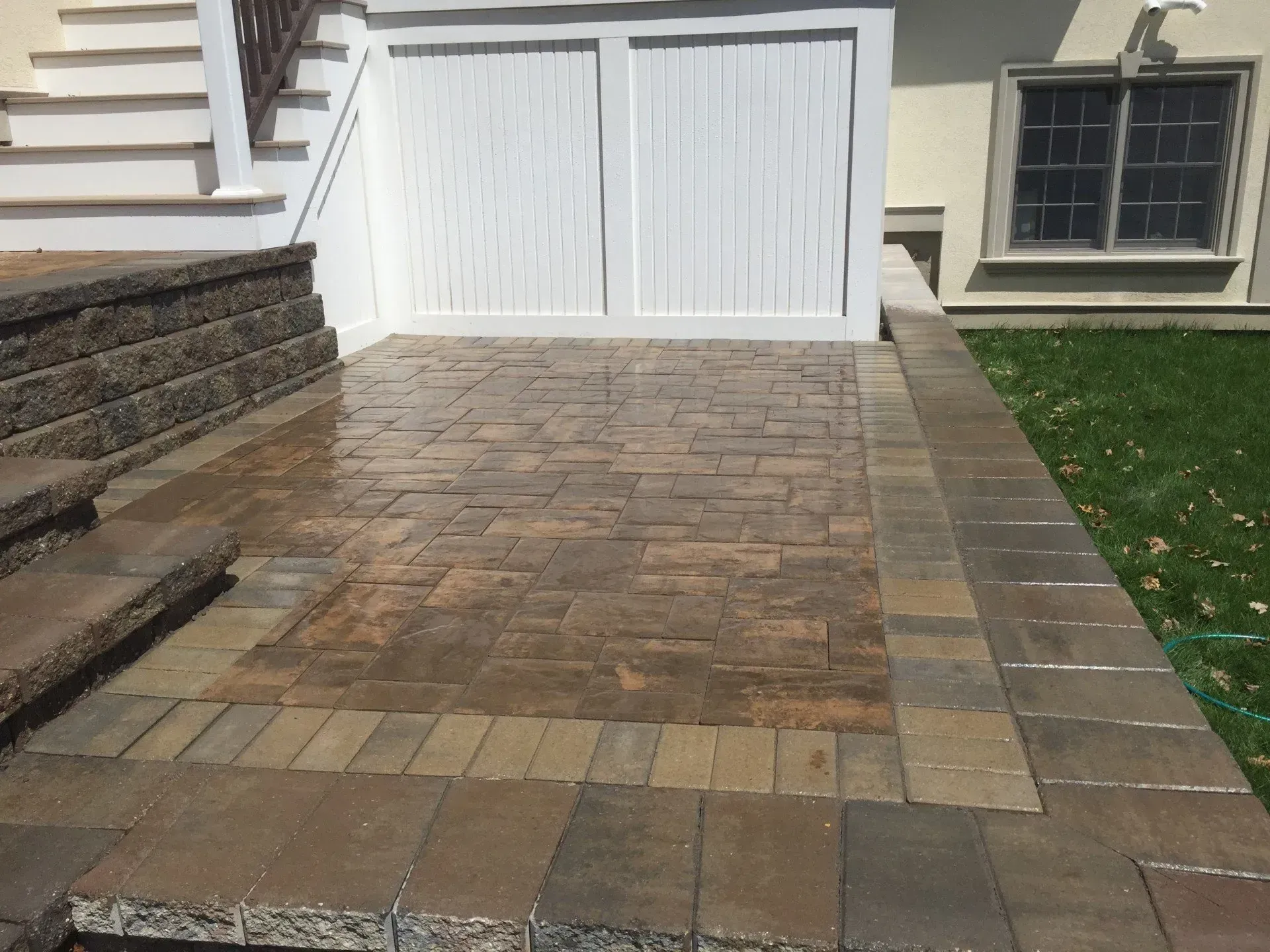 A brick walkway leading to a white garage door