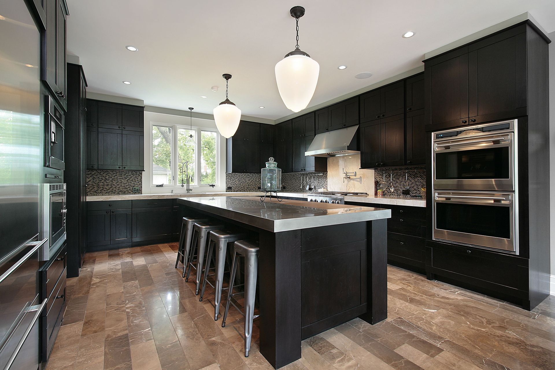 Modern black kitchen with island, pendant lights, bar stools, and hardwood floors