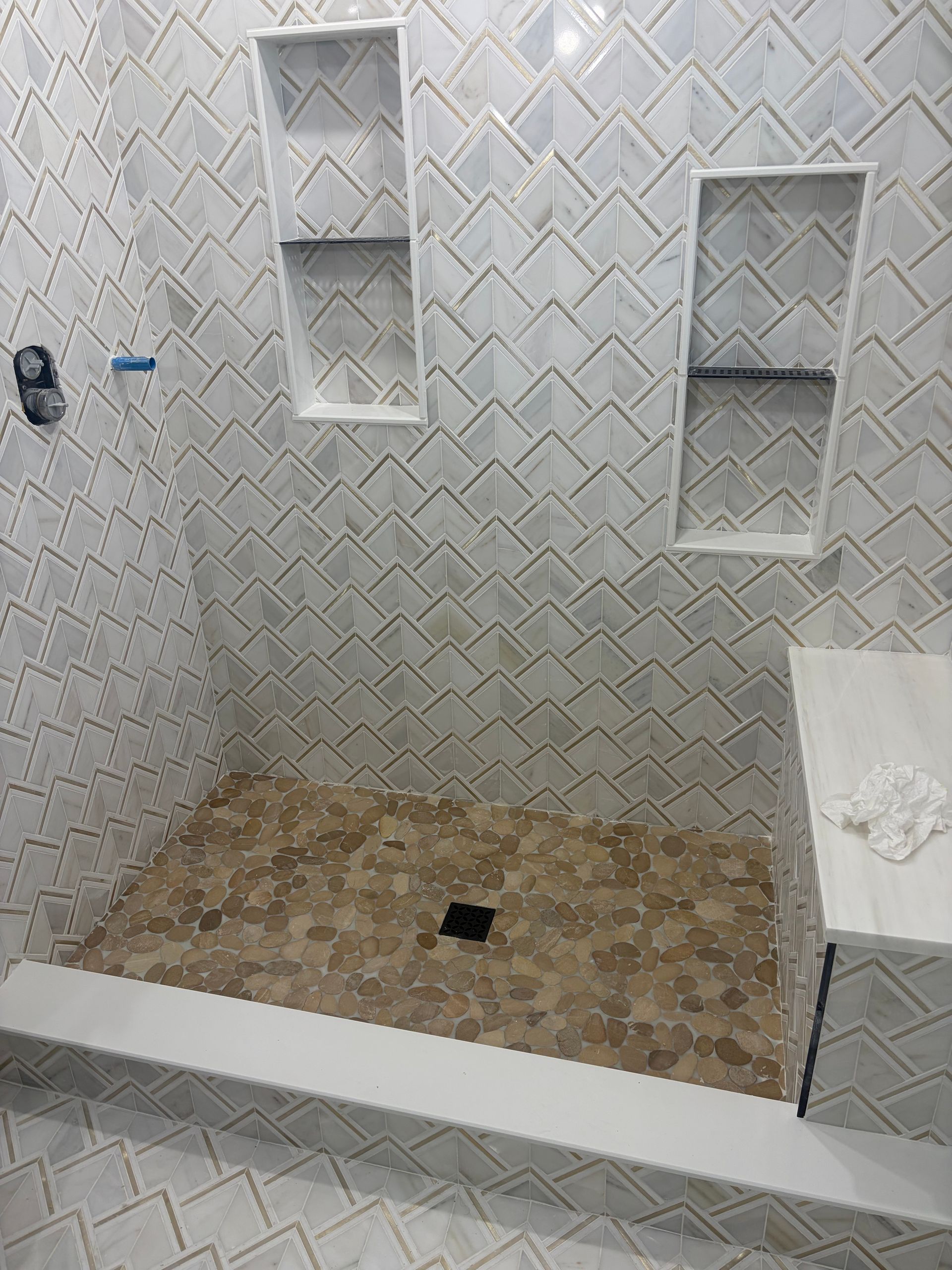 Empty tiled shower stall with built-in niches and a small step-up platform.