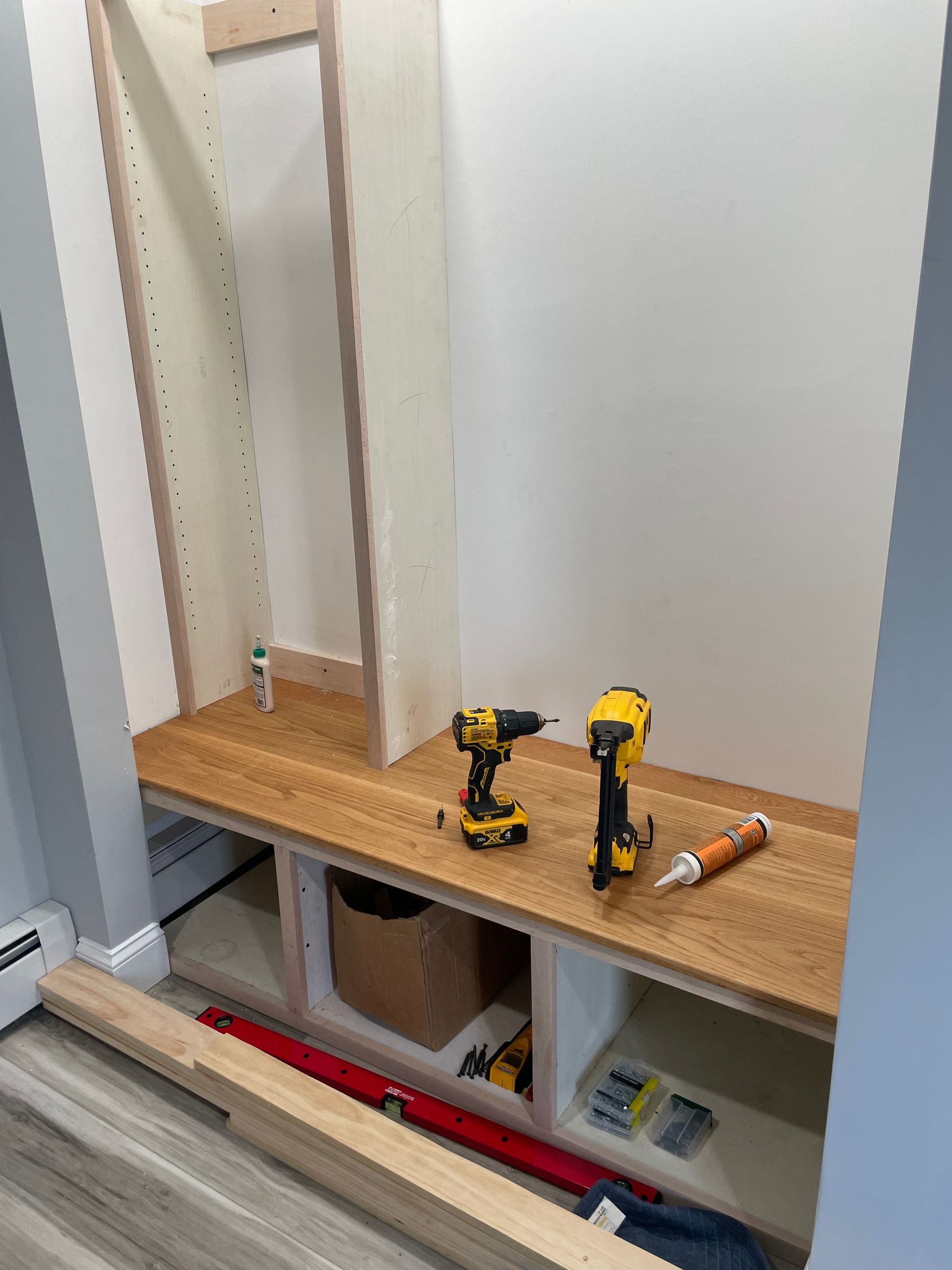 Built-in cabinet under construction with two drills and tools on a wooden shelf