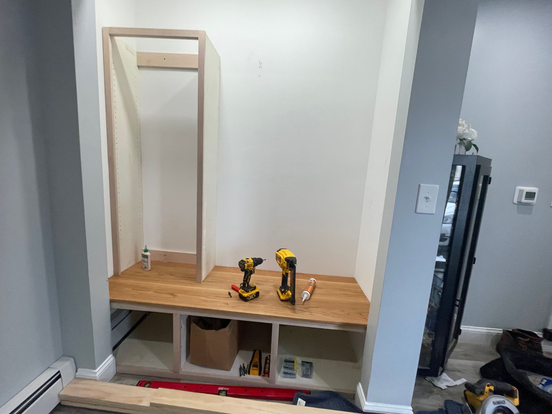 Built-in bench with wooden shelf, mirror, and tools in a hallway alcove