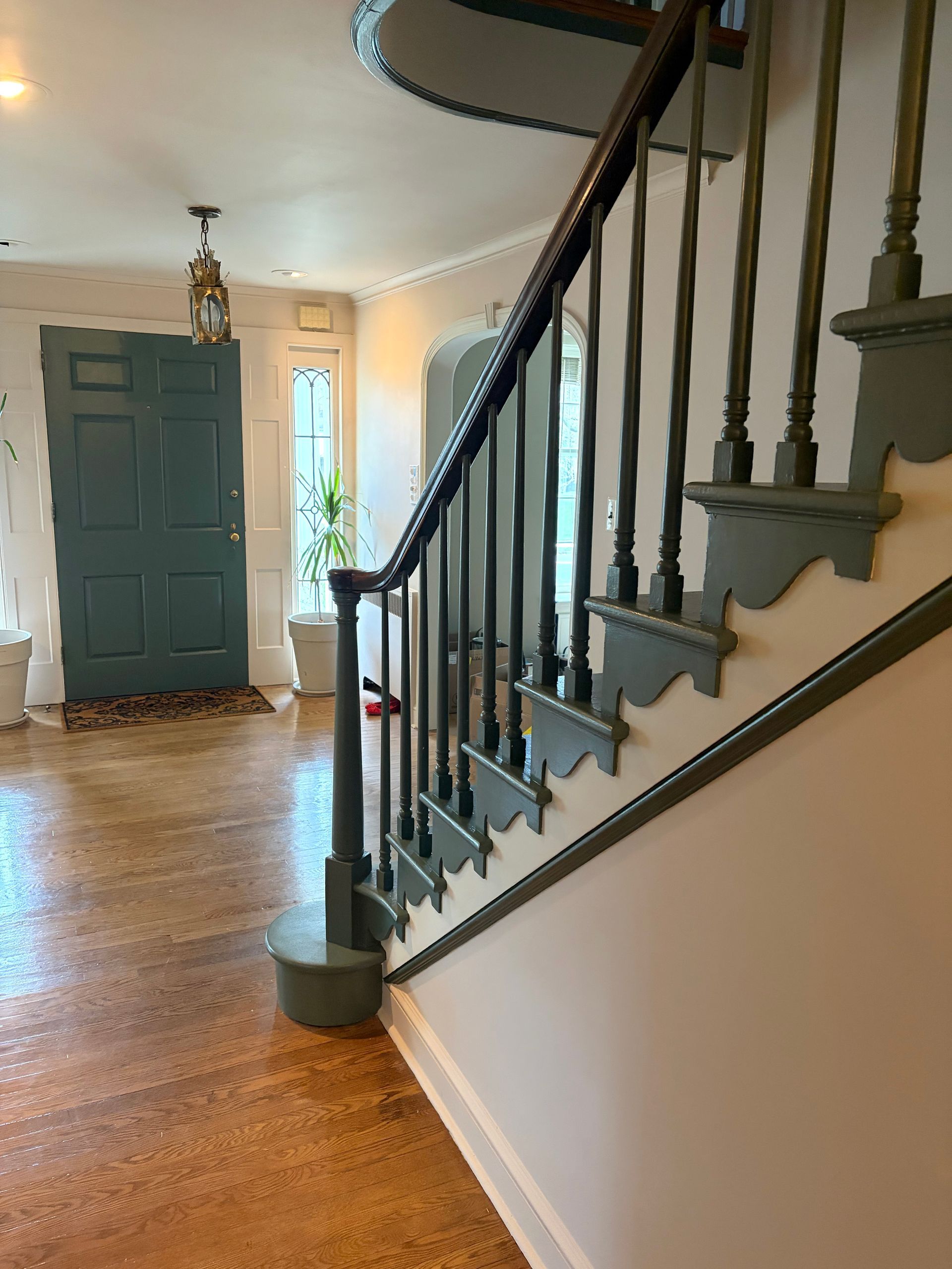Entryway with hardwood floors, blue front door, and staircase with dark railing and white wall.