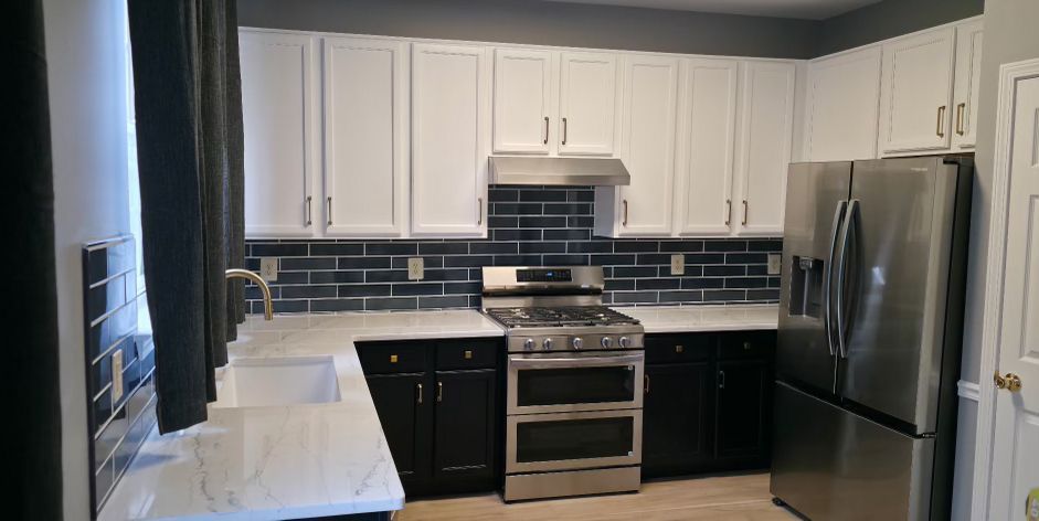 Modern kitchen with white cabinets, black countertops, stainless steel appliances, and blue tile backsplash