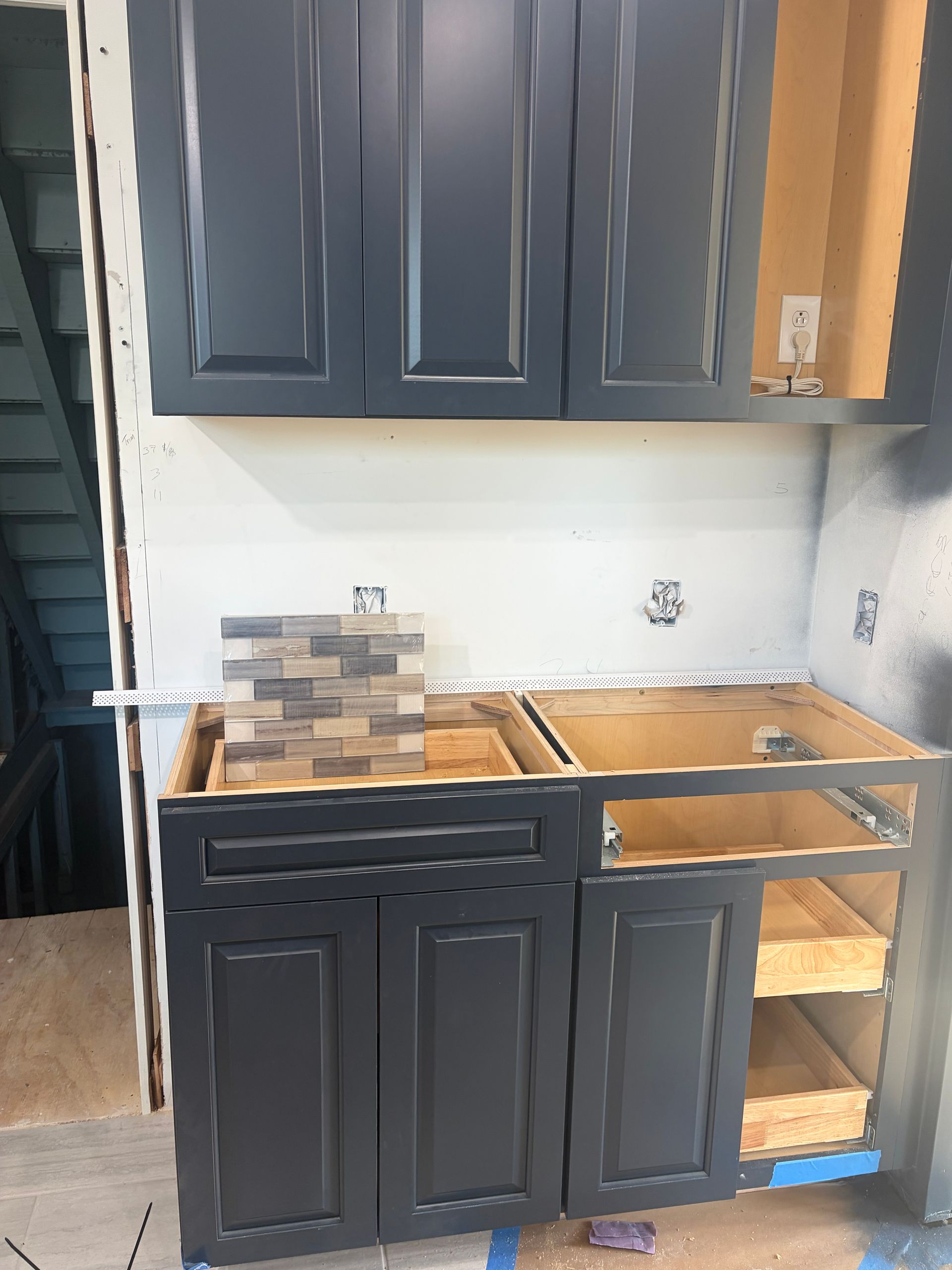 Partially installed dark blue kitchen cabinets and countertops under renovation