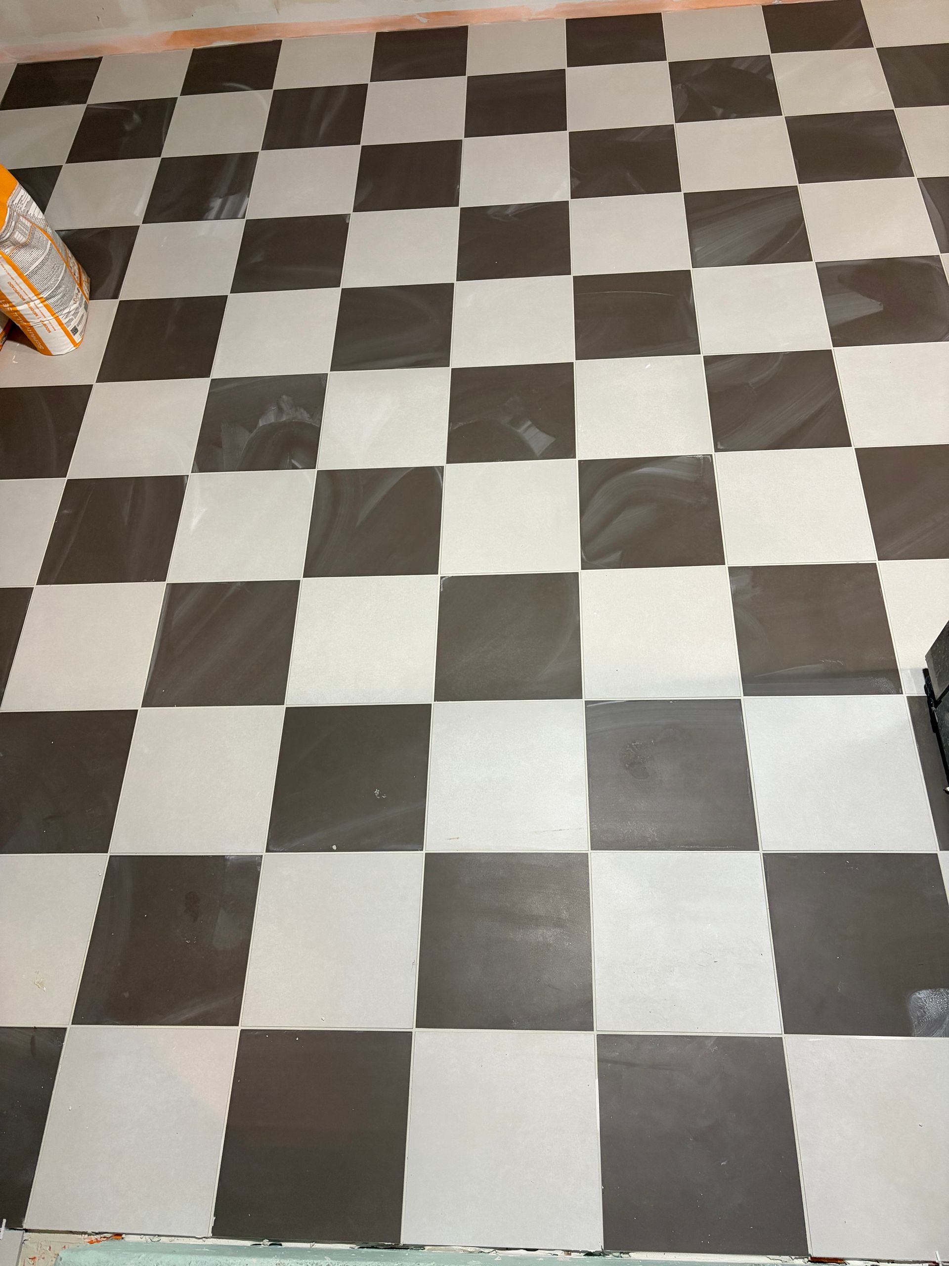 Black-and-white checkered tile floor in an indoor room, viewed from above.