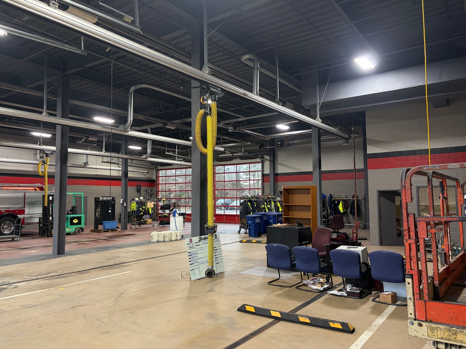 Empty auto shop with lifts, tools, and chairs under bright overhead lights.
