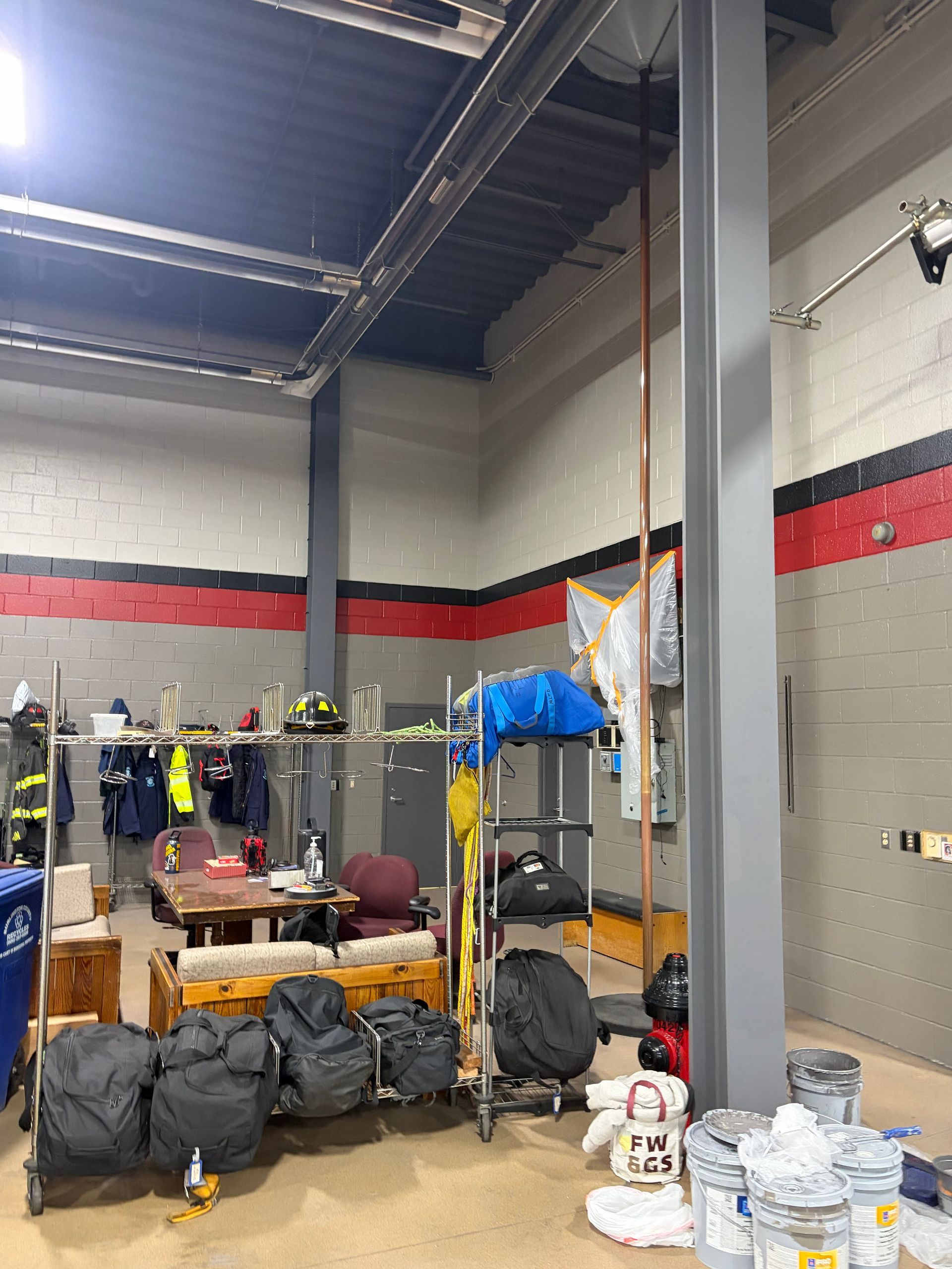 Warehouse storage area with stacked bags, shelves, and boxes under a high ceiling
