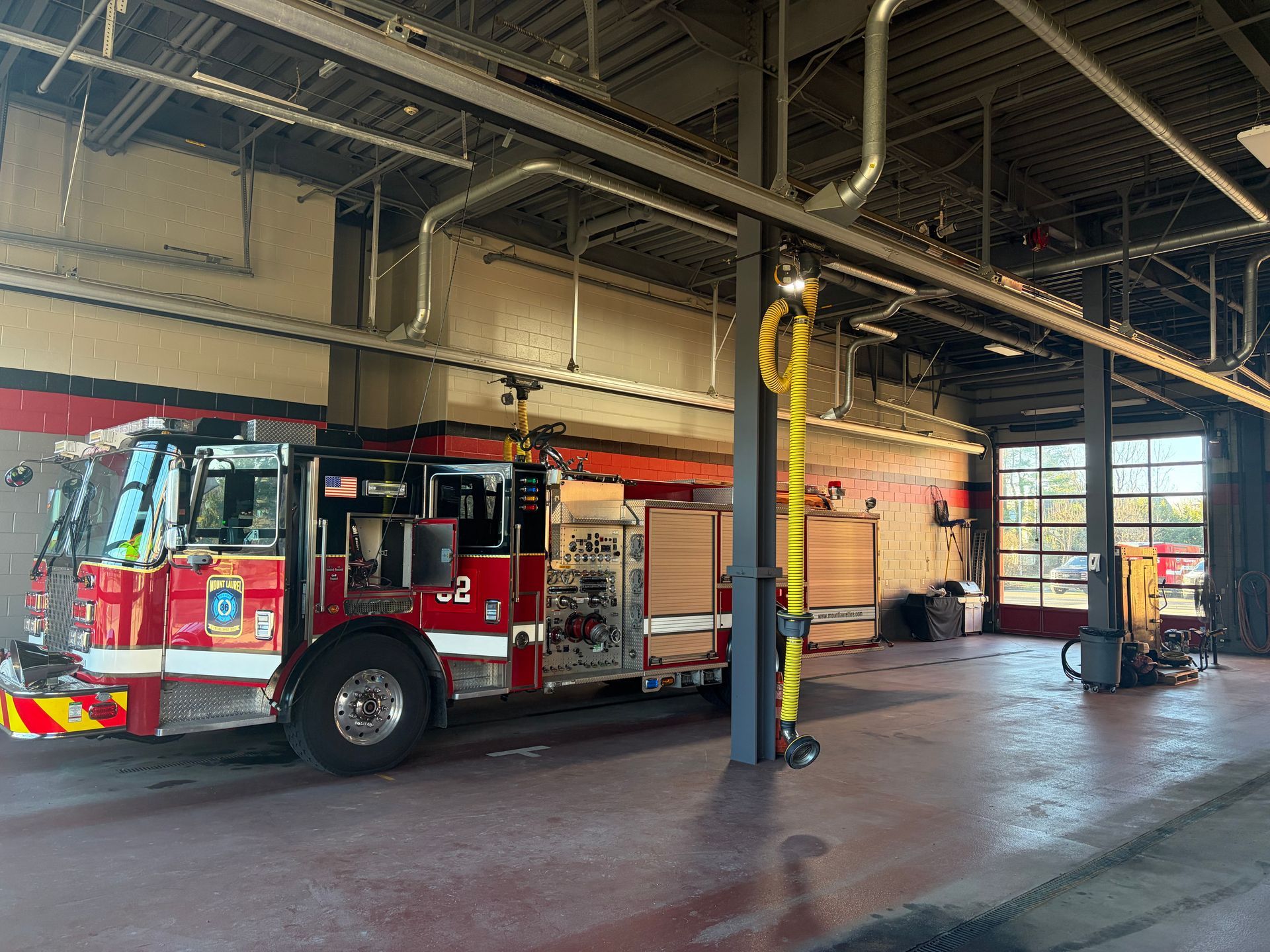 Fire truck parked inside a fire station bay with open garage doors and equipment columns