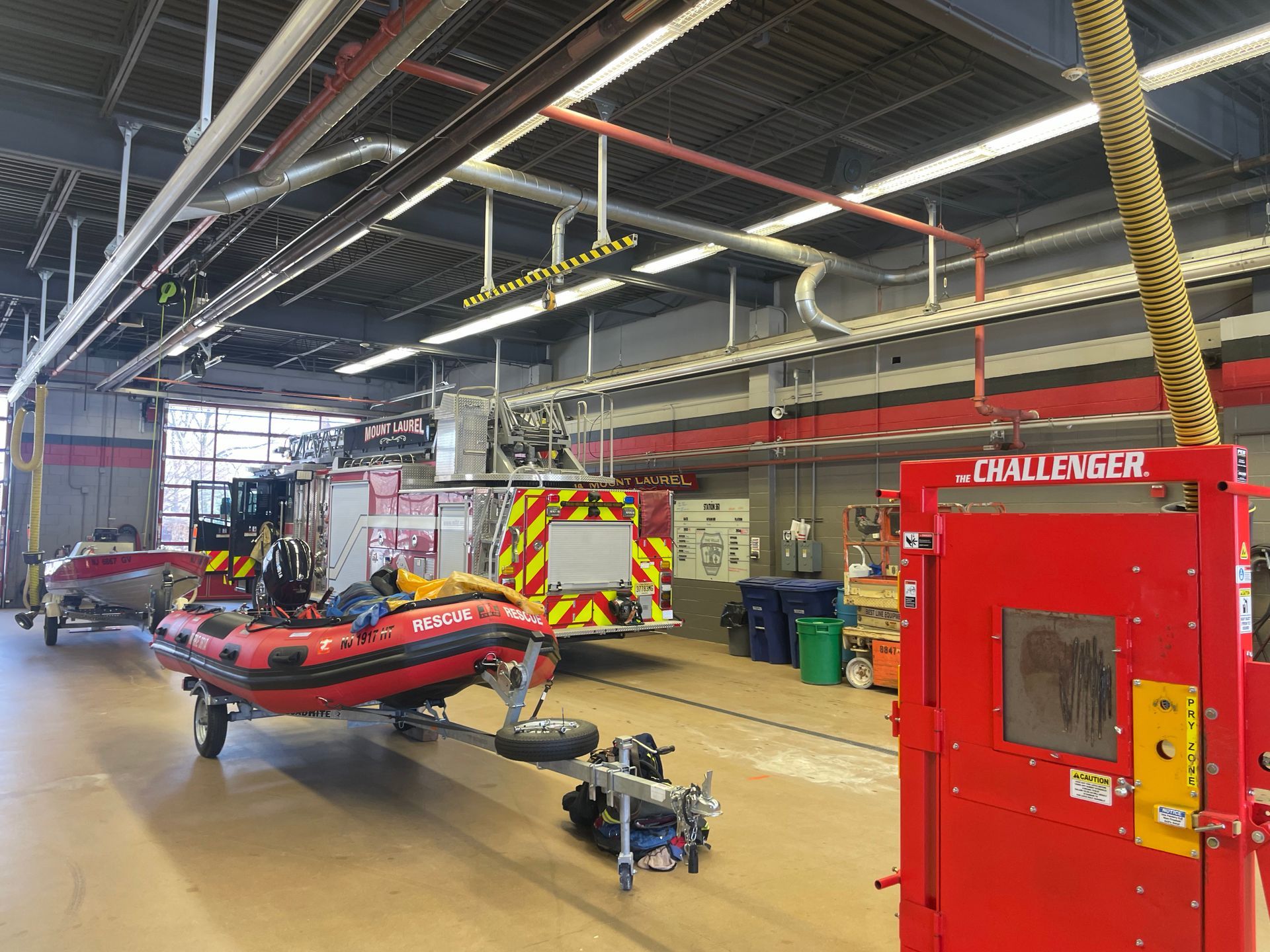 Fire station bay with a red emergency vehicle, equipment, and an open garage door