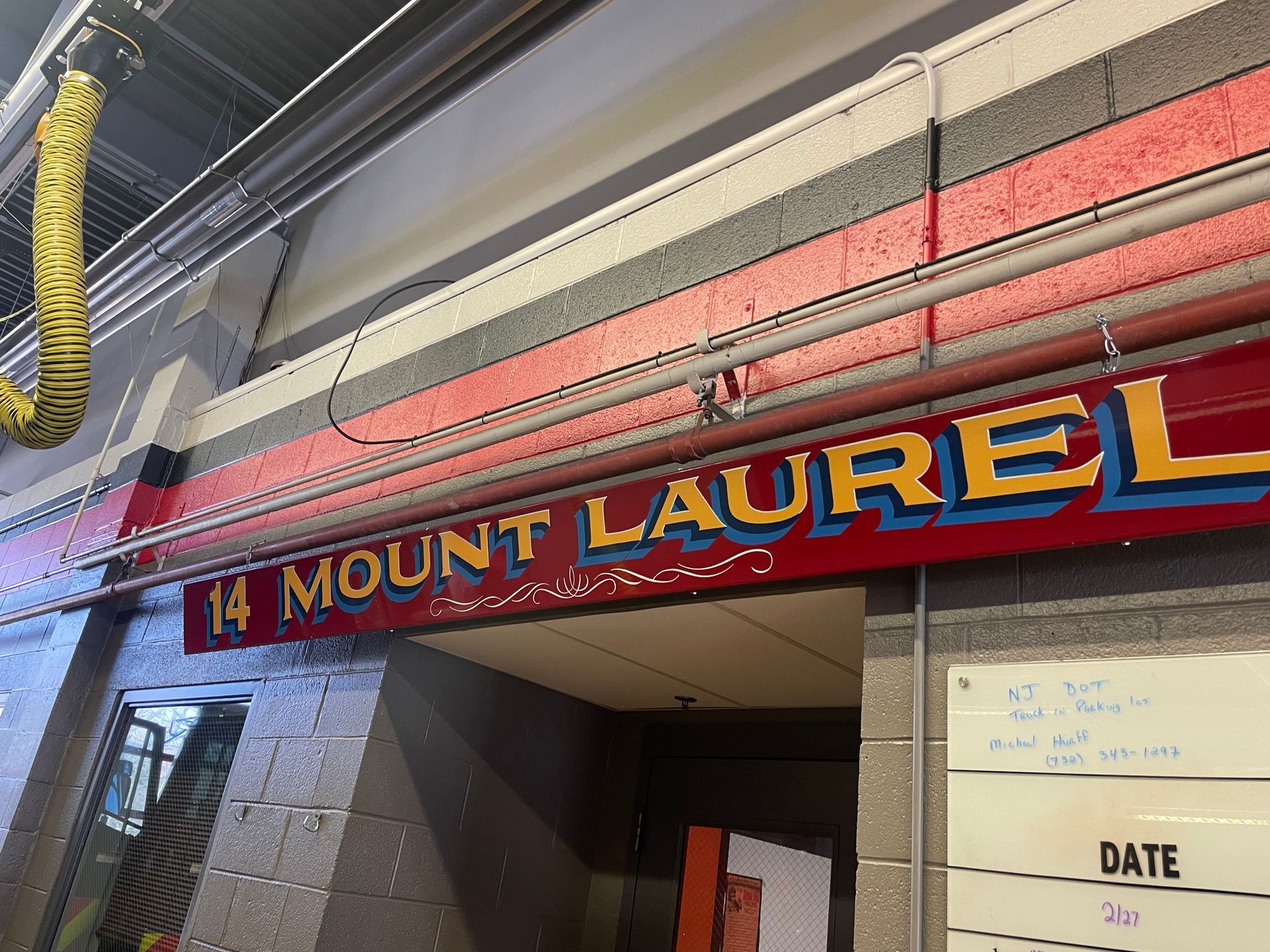 Entrance sign reading “14 Mount Laurel” above a hallway, with a yellow duct on the left.