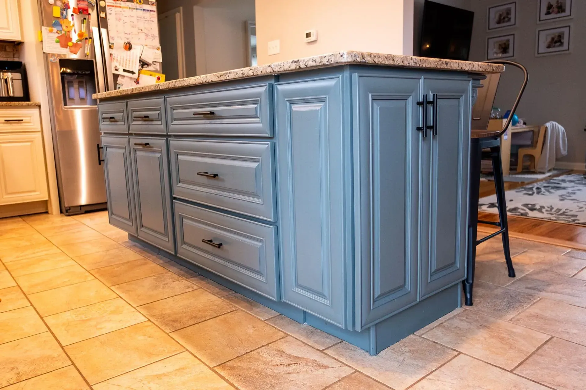Kitchen island with blue cabinets, granite countertop, drawers, and black hardware.