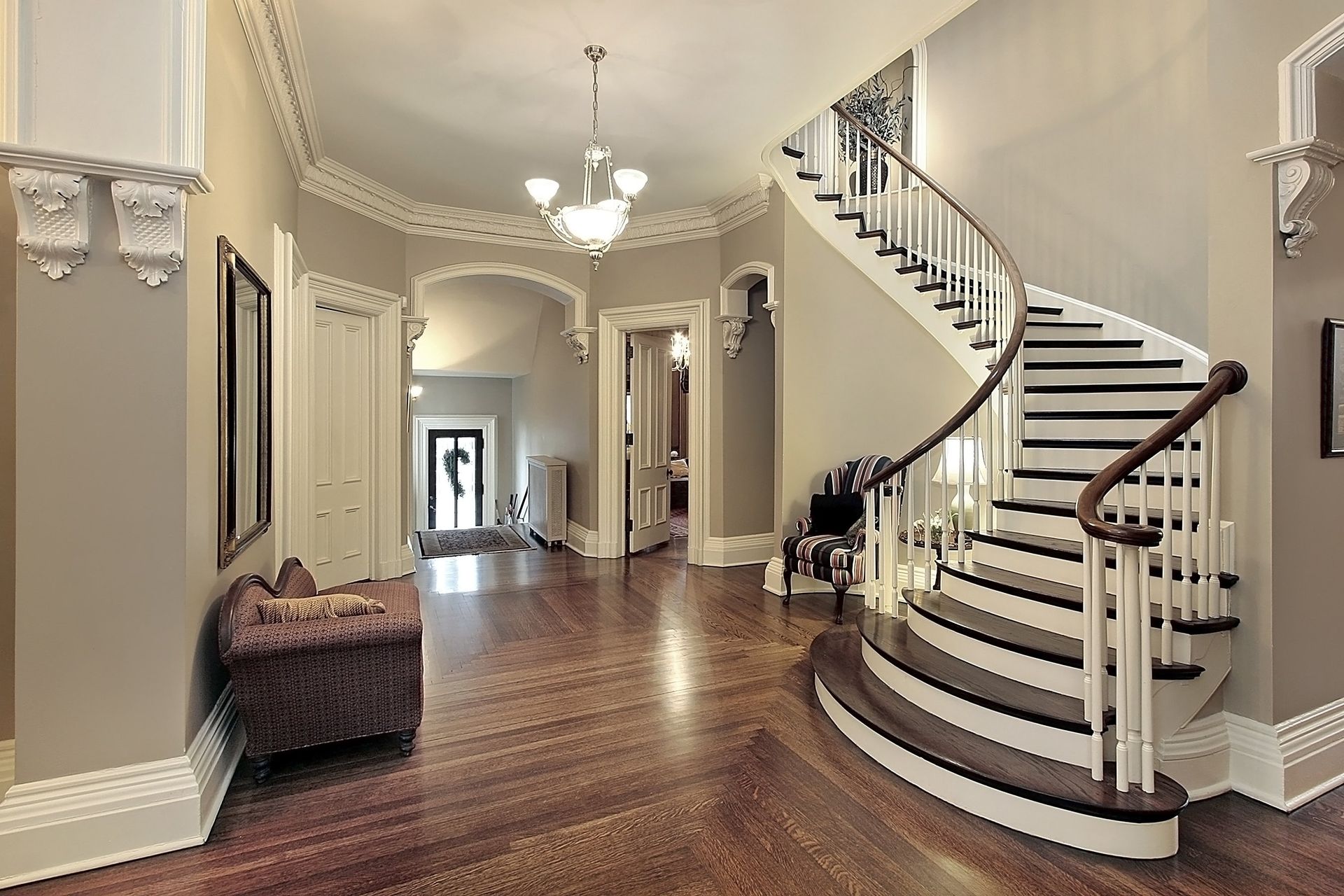 Elegant foyer with curved staircase, hardwood floors, and chandelier lighting