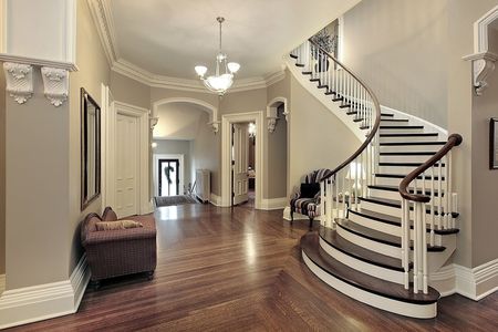 Elegant foyer with curved staircase, hardwood floors, and chandelier lighting