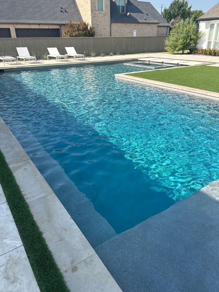A large swimming pool with a house in the background
